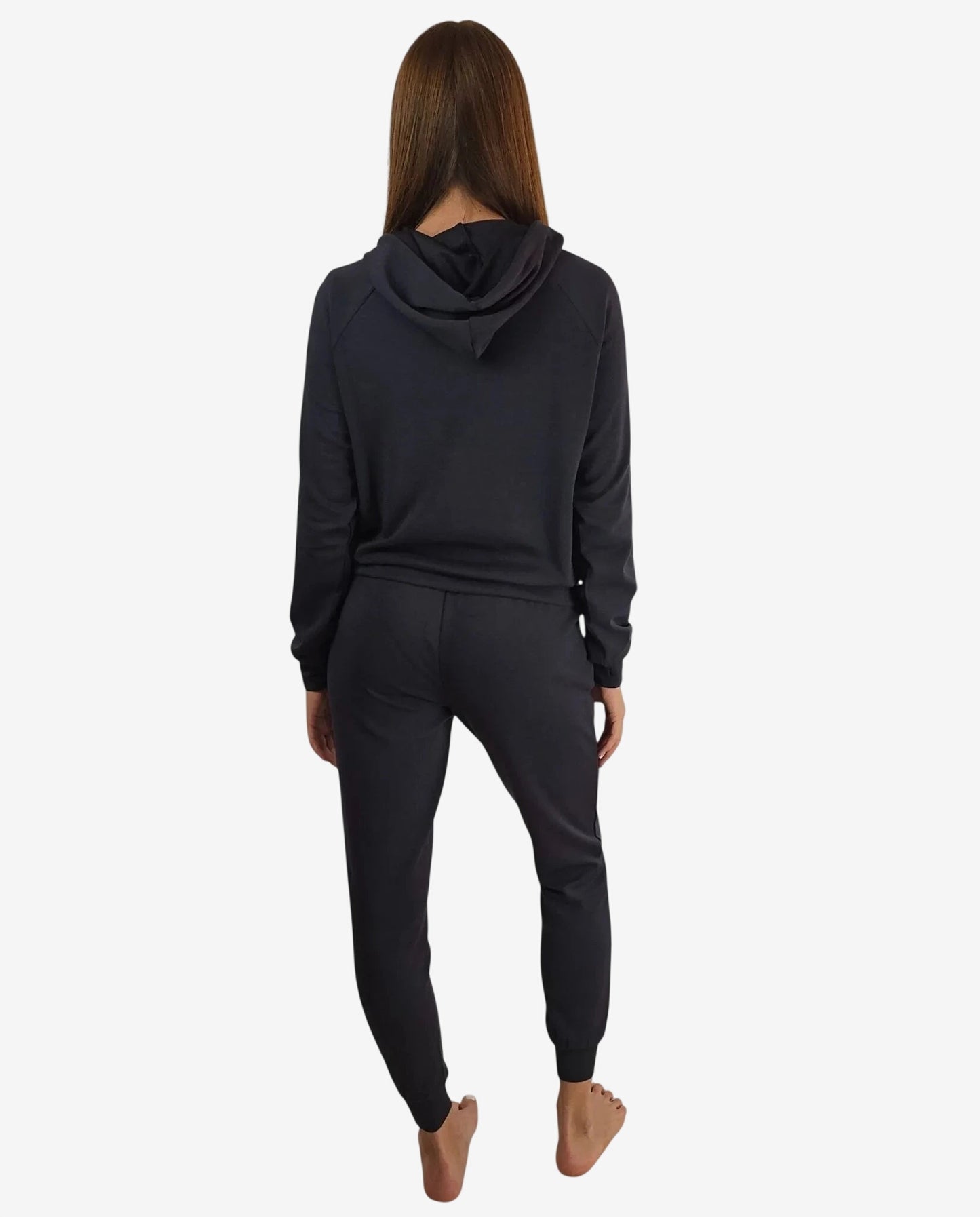 Donna di spalle che indossa una tuta sportiva nera con cappuccio e pantaloni coordinati.