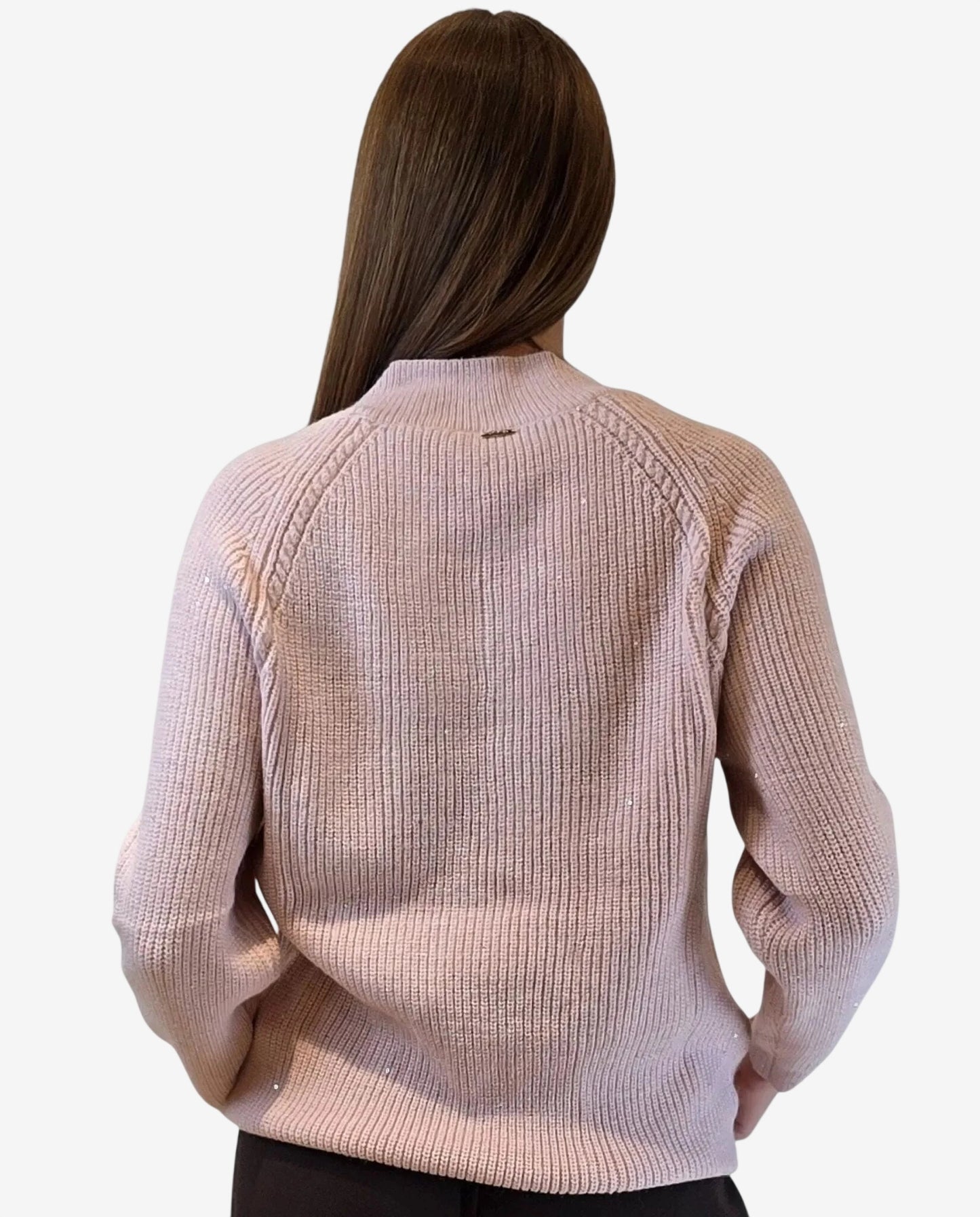 A woman wears a light pink ribbed knit pullover with subtle sequin accents and a mock neck.