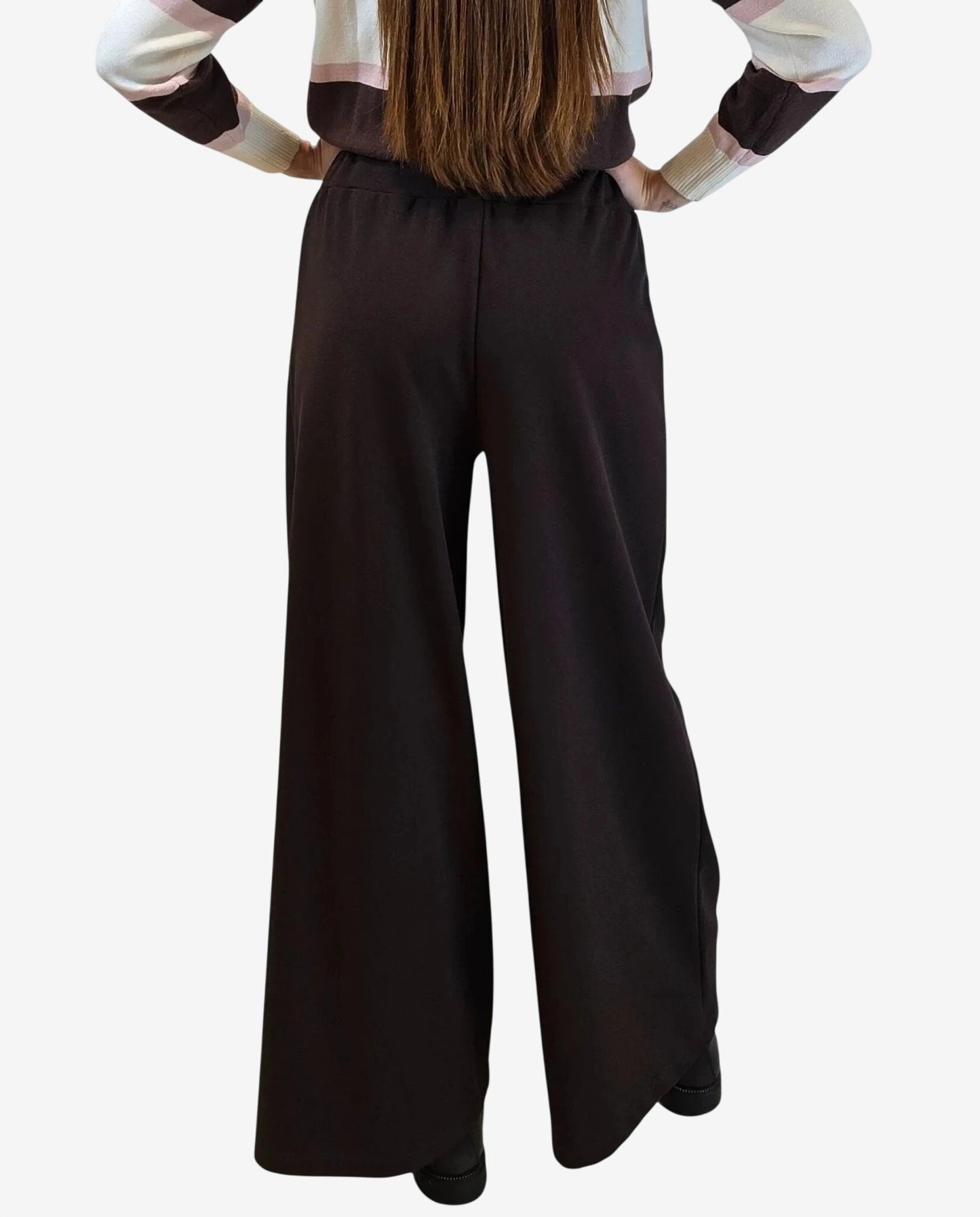 A person from behind wearing dark brown wide-leg trousers with an elastic waistband.