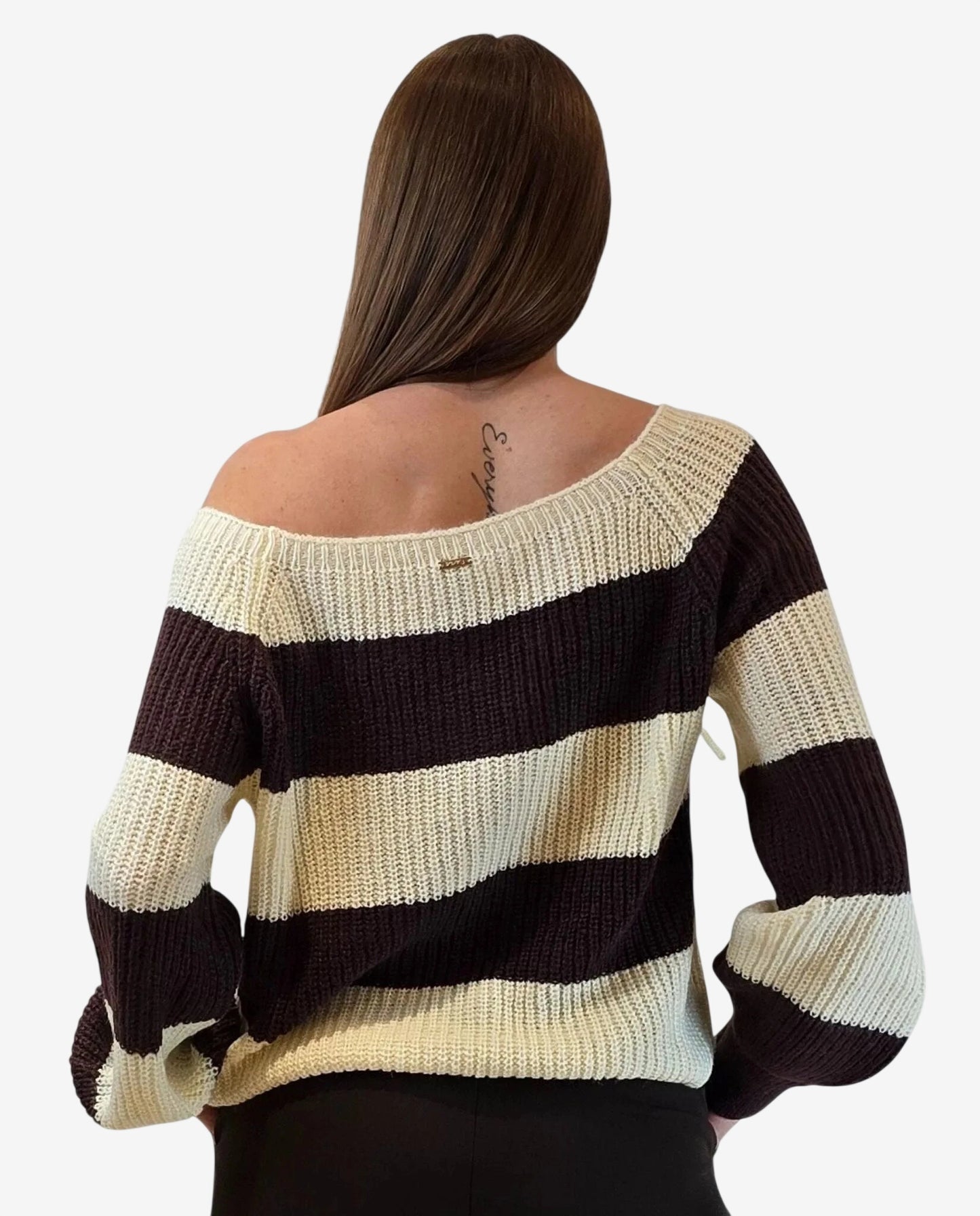 A woman wears a long-sleeved, off-the-shoulder pullover sweater with horizontal cream and brown stripes.