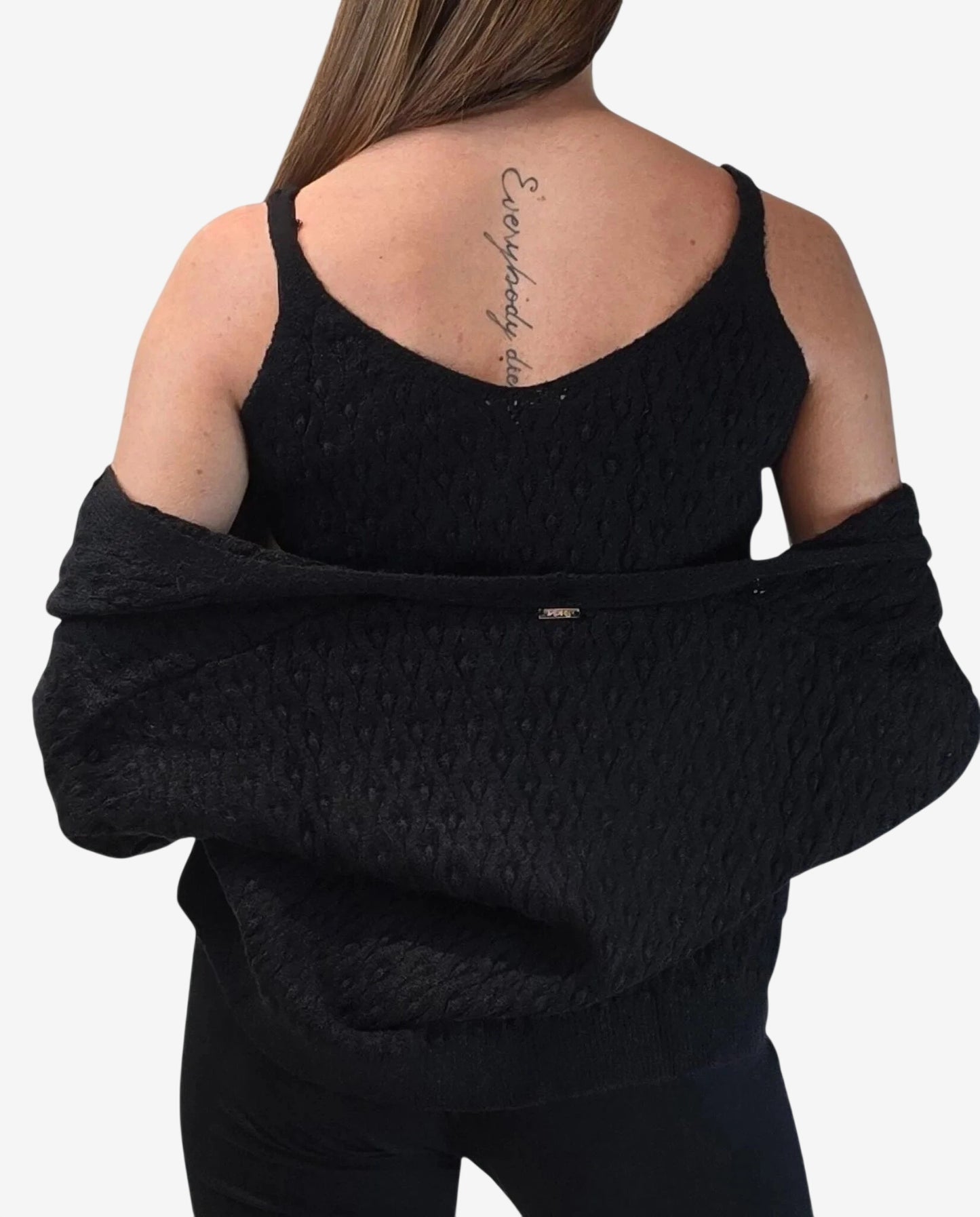 A woman wears a black textured tank top and a matching cardigan draped off her shoulders.
