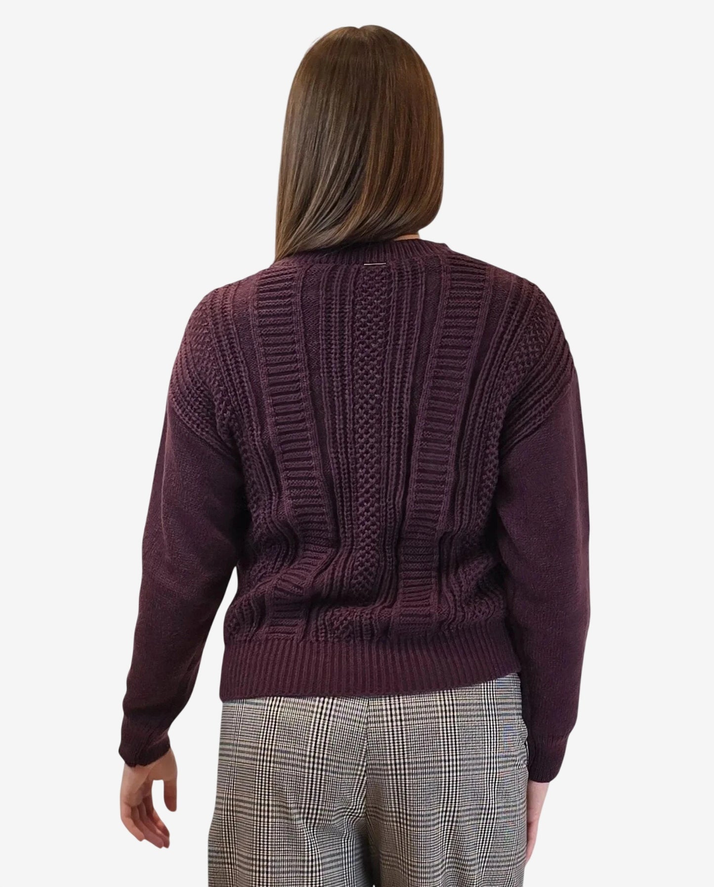 A woman wears a long-sleeved, burgundy cable-knit pullover sweater from the back.