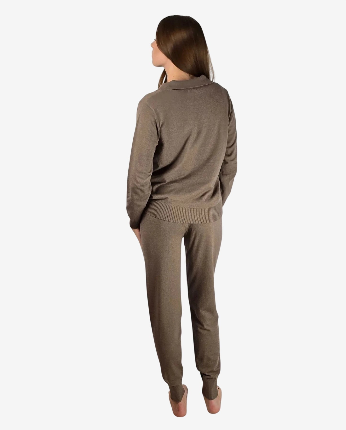 Una donna indossa una tuta in maglia color marrone composta da maglia a polo e pantaloni con polsini.