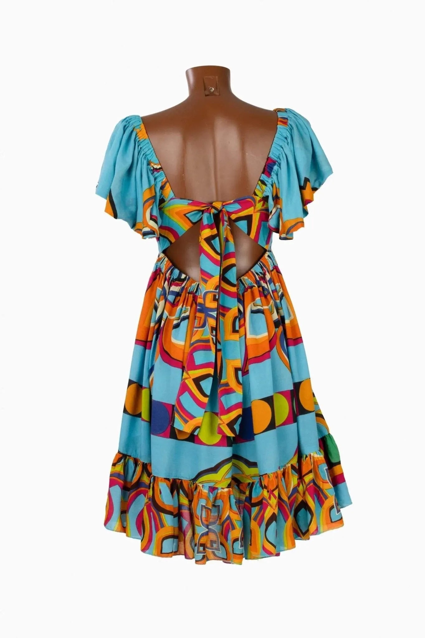 Abito corto multicolore con schiena scoperta, allacciatura a fiocco e volant sulle spalle.