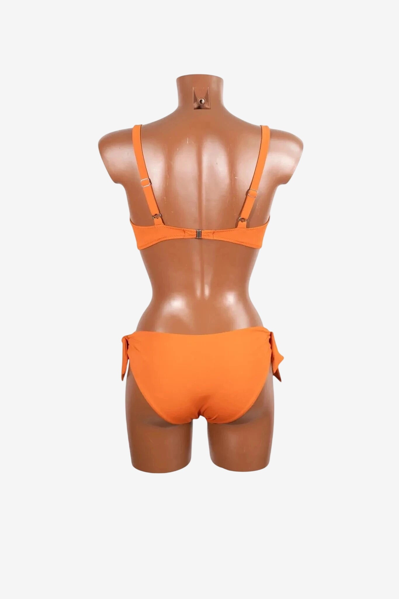 A back view of an orange bikini set with a clasp closure and side-tie bottoms on a mannequin.