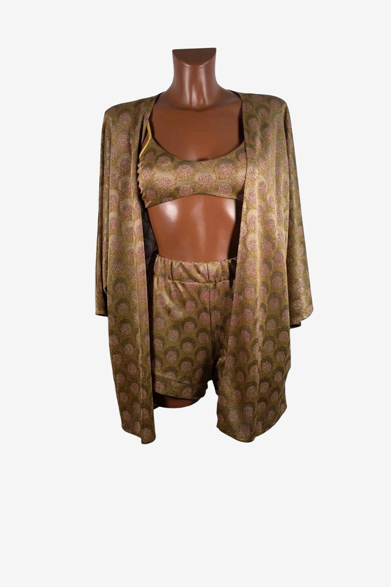 A three-piece set featuring a kimono, crop top, and shorts in a metallic gold and pink circle print.