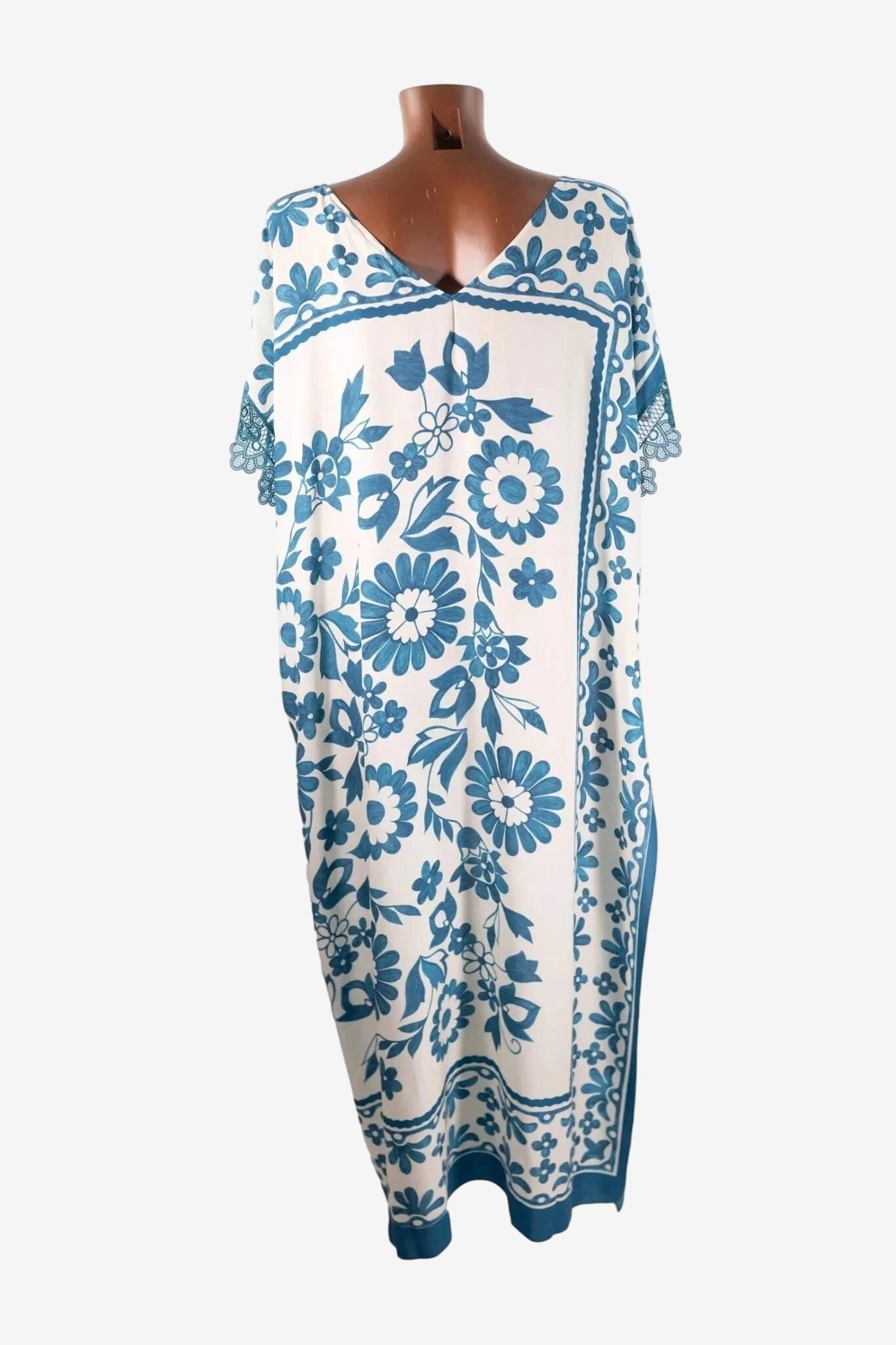 Caftano lungo in viscosa bianca con stampa floreale blu e dettagli in pizzo macramè sulle maniche.