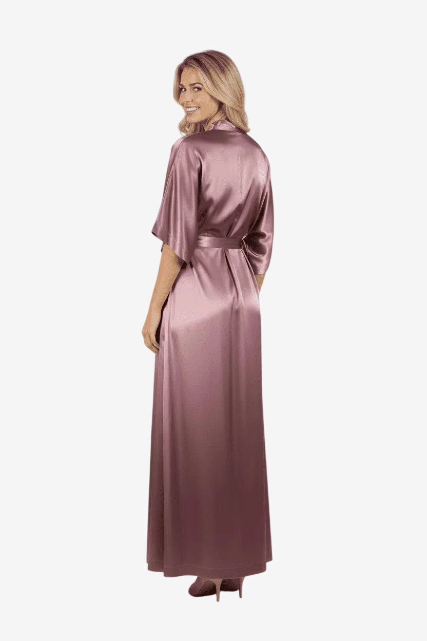 Una donna indossa un abito lungo in raso color malva con maniche a kimono e cintura in vita.