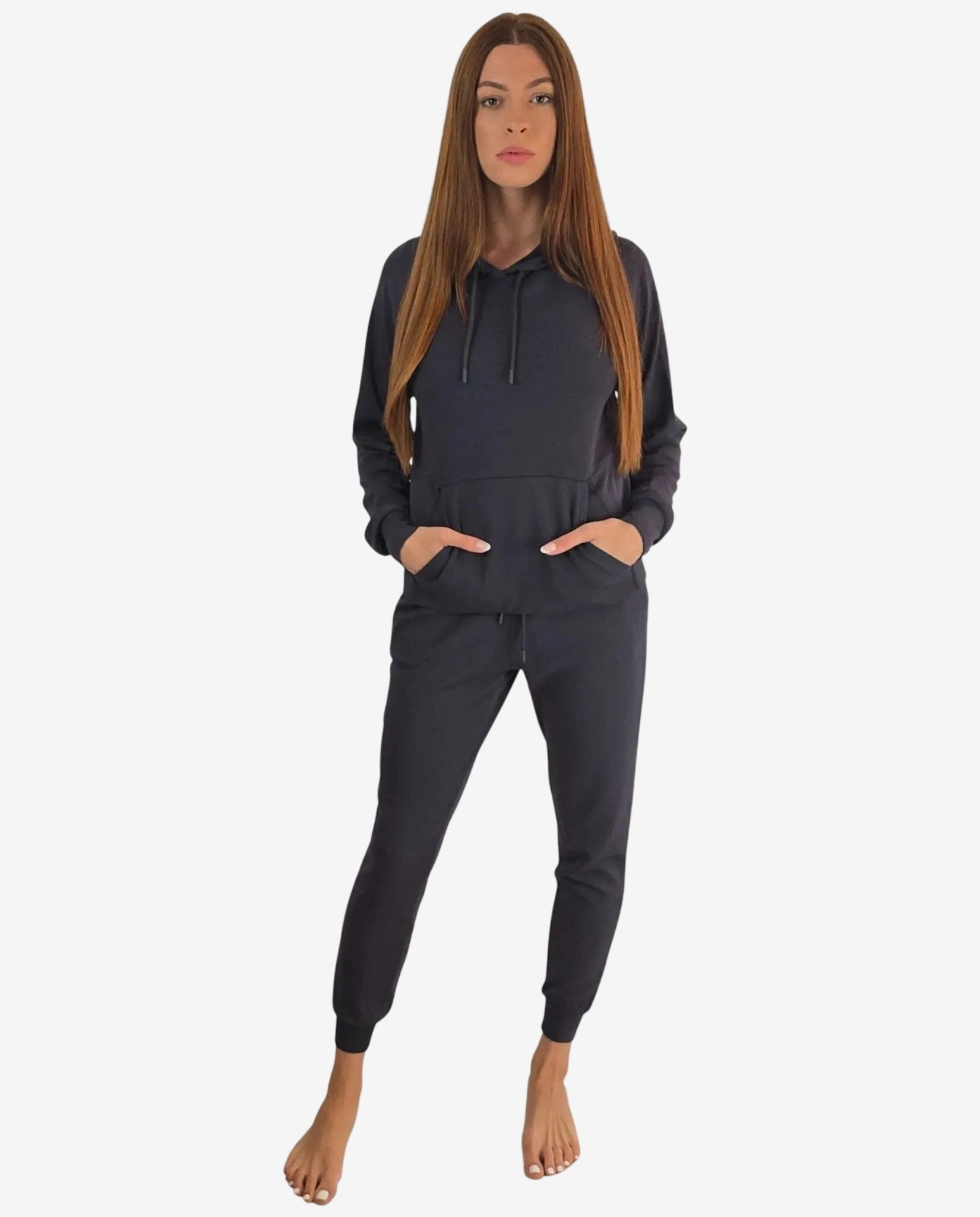 Modella che indossa una tuta sportiva grigio scuro con felpa a cappuccio e pantaloni coordinati.