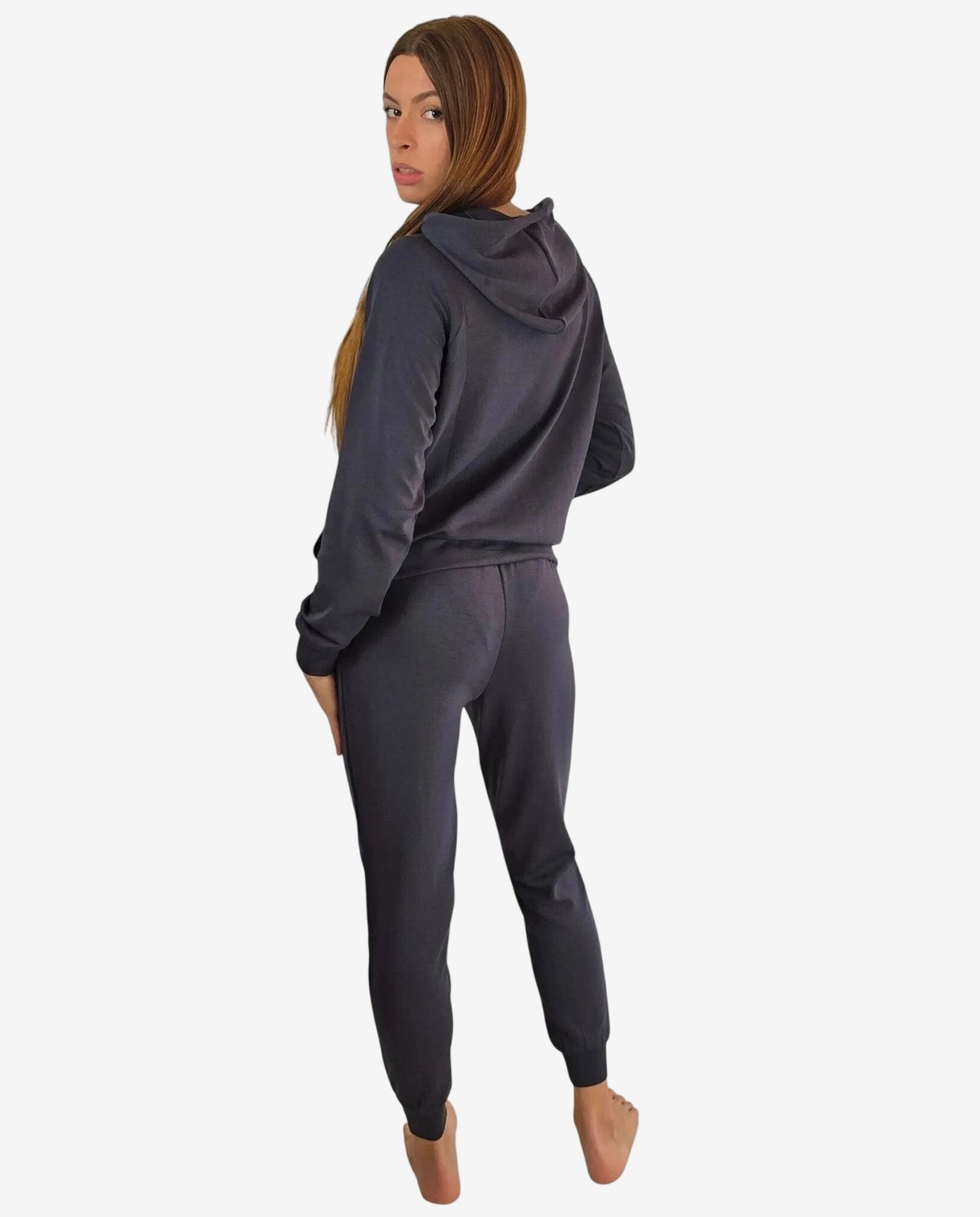 Donna che indossa una tuta sportiva grigio scuro con cappuccio vista da dietro.