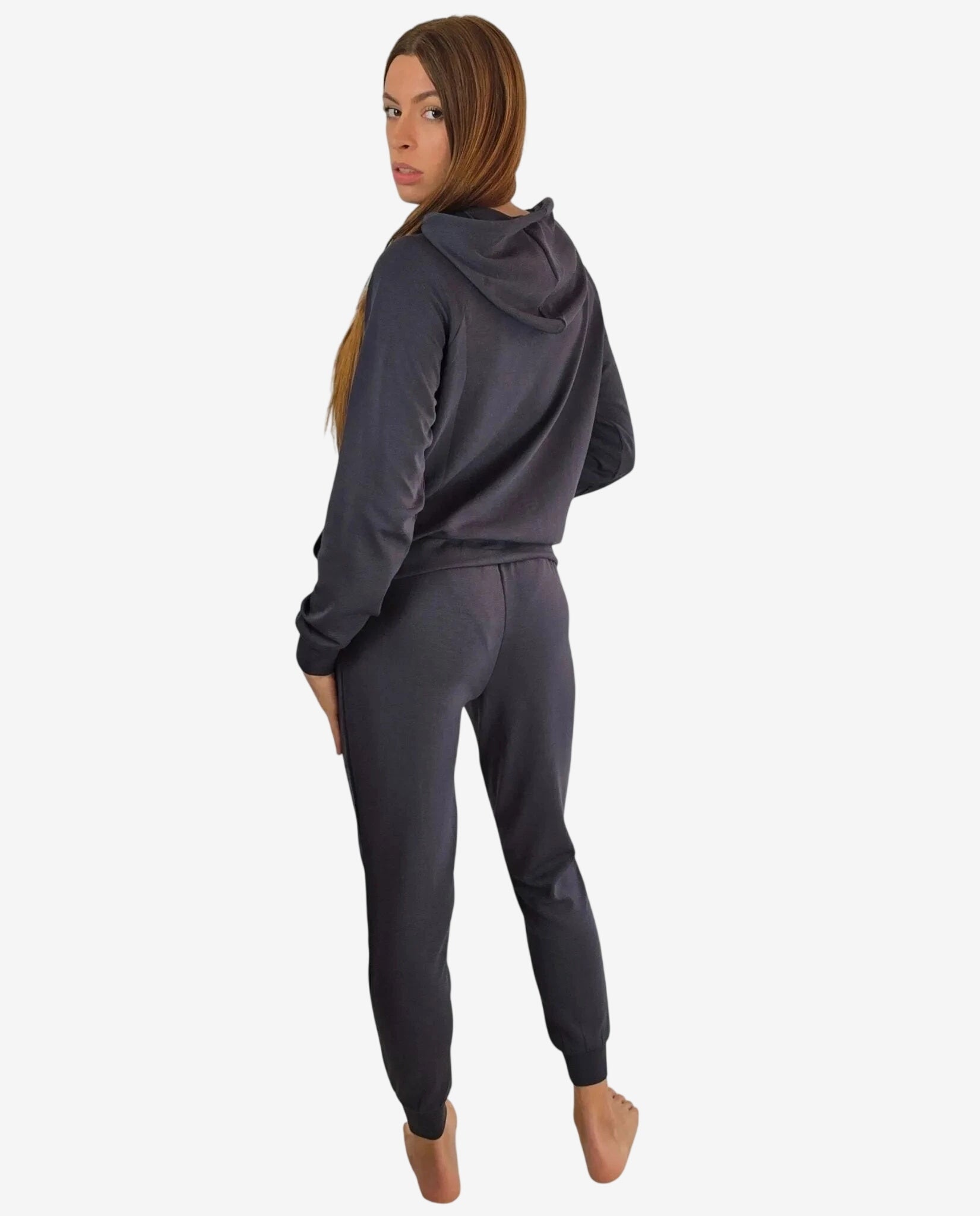 Donna che indossa una tuta sportiva grigio scuro con cappuccio vista da dietro.