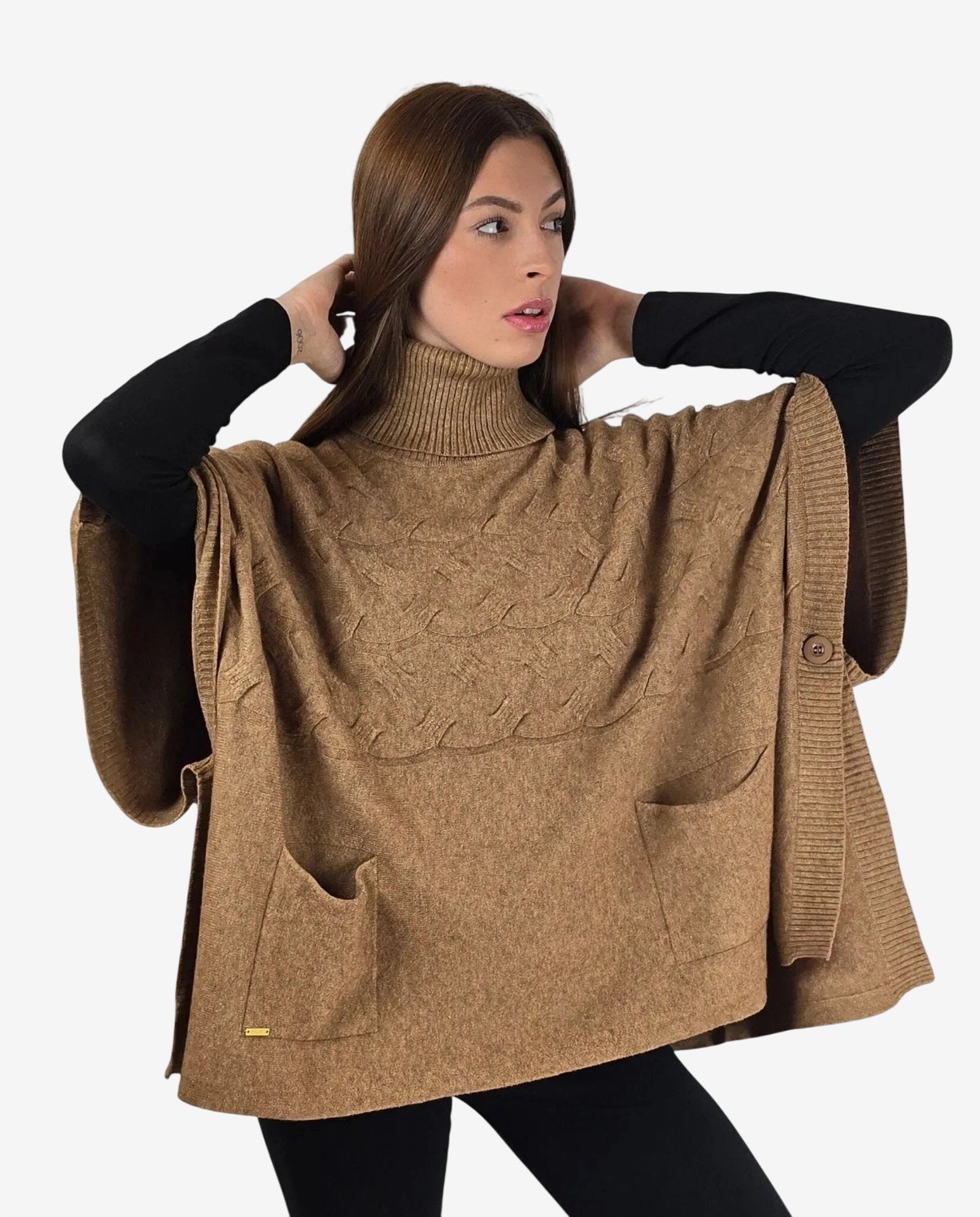 Modella indossa un poncho color cammello a collo alto con tasche frontali e dettagli a trecce.