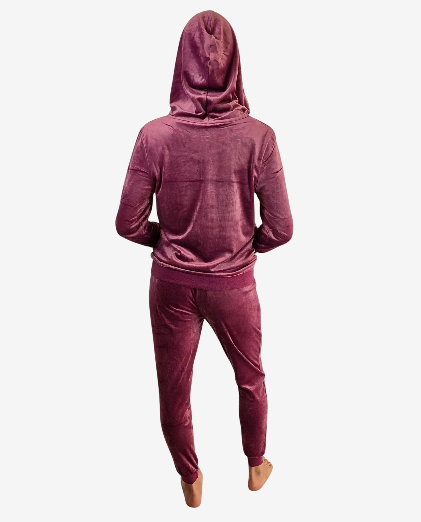 A person wearing a dark pink velour tracksuit with a hooded sweatshirt and matching joggers.