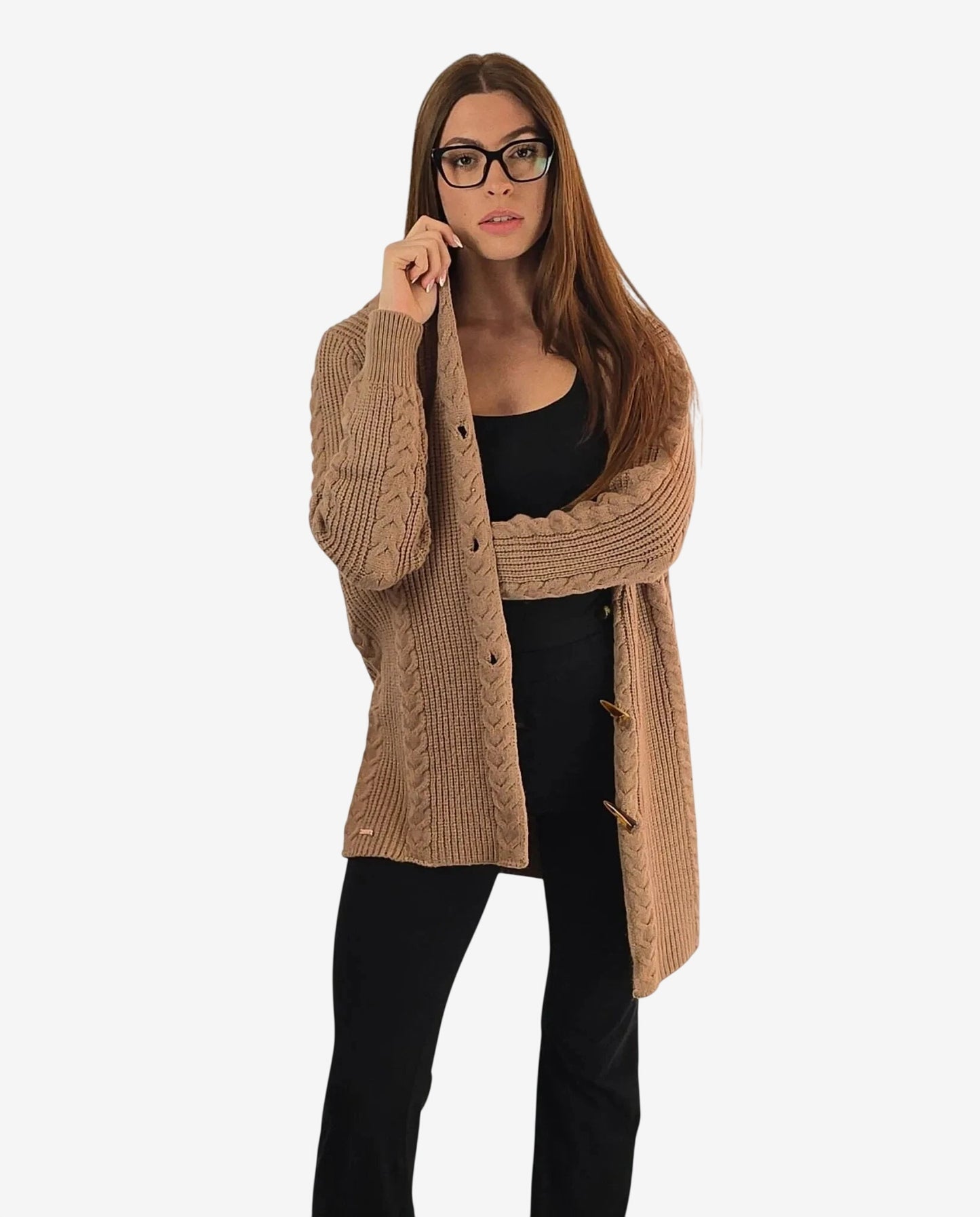 Cardigan beige lavorato a treccia con chiusura a alamari indossato sopra un completo nero.