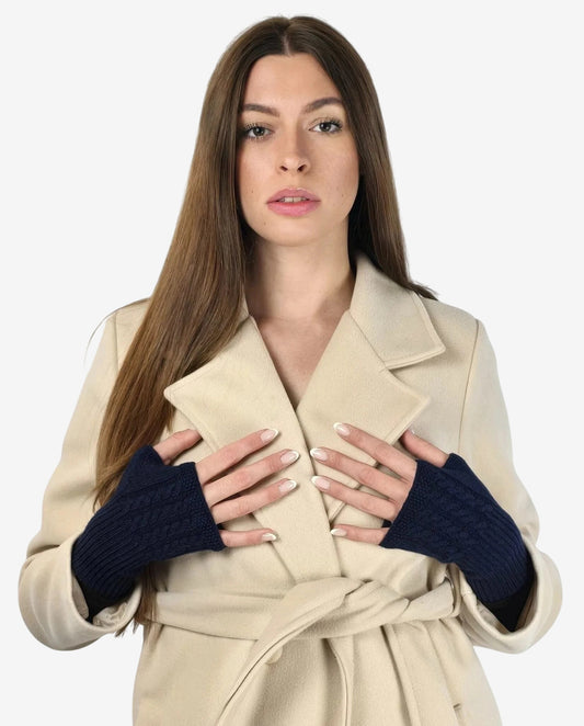 Donna che indossa manicotti in cachemire blu a trecce sopra un cappotto color crema.