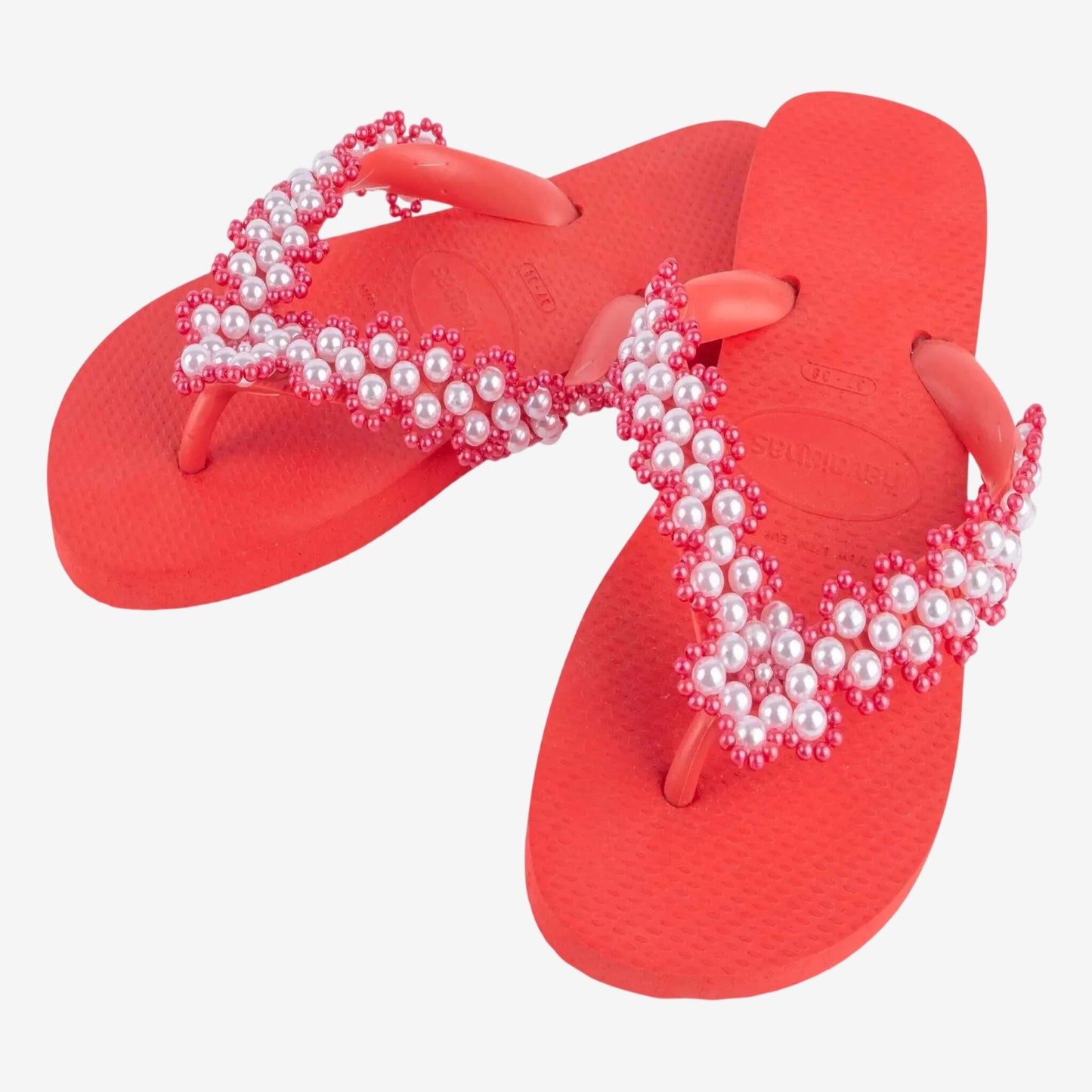 Infradito Havaianas rosse con cinturini decorati da un ricamo artigianale di perle bianche.