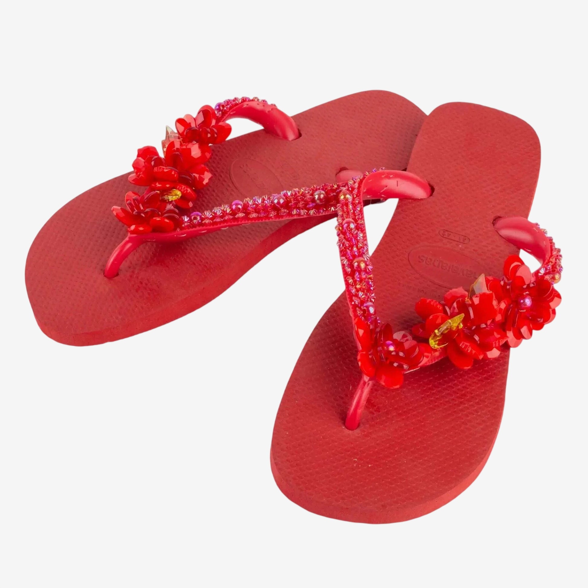 Infradito Havaianas rosse decorate con fiori e pietre preziose applicate a mano.
