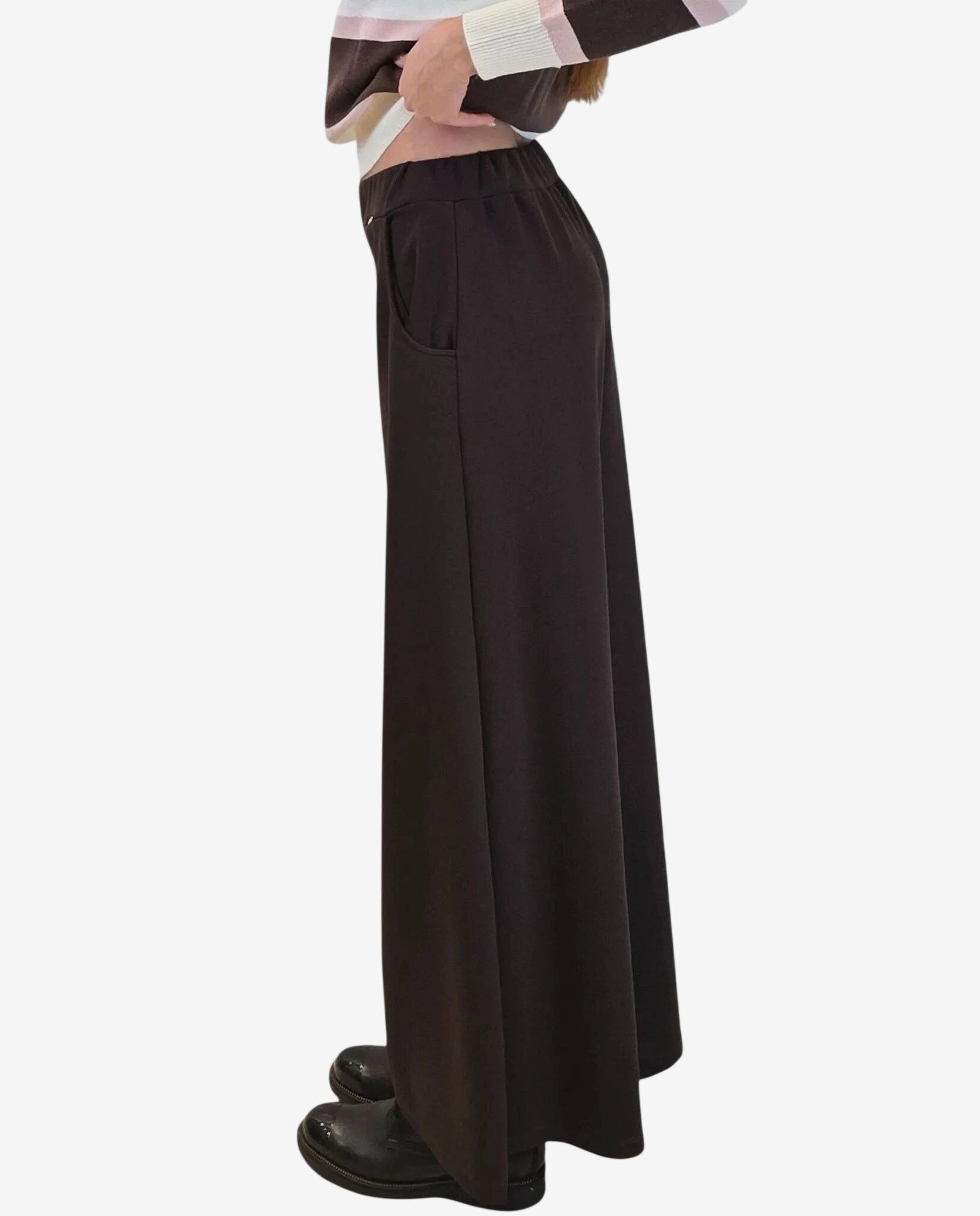 A person wearing mocha-colored wide-leg trousers with an elastic waistband and side pockets.