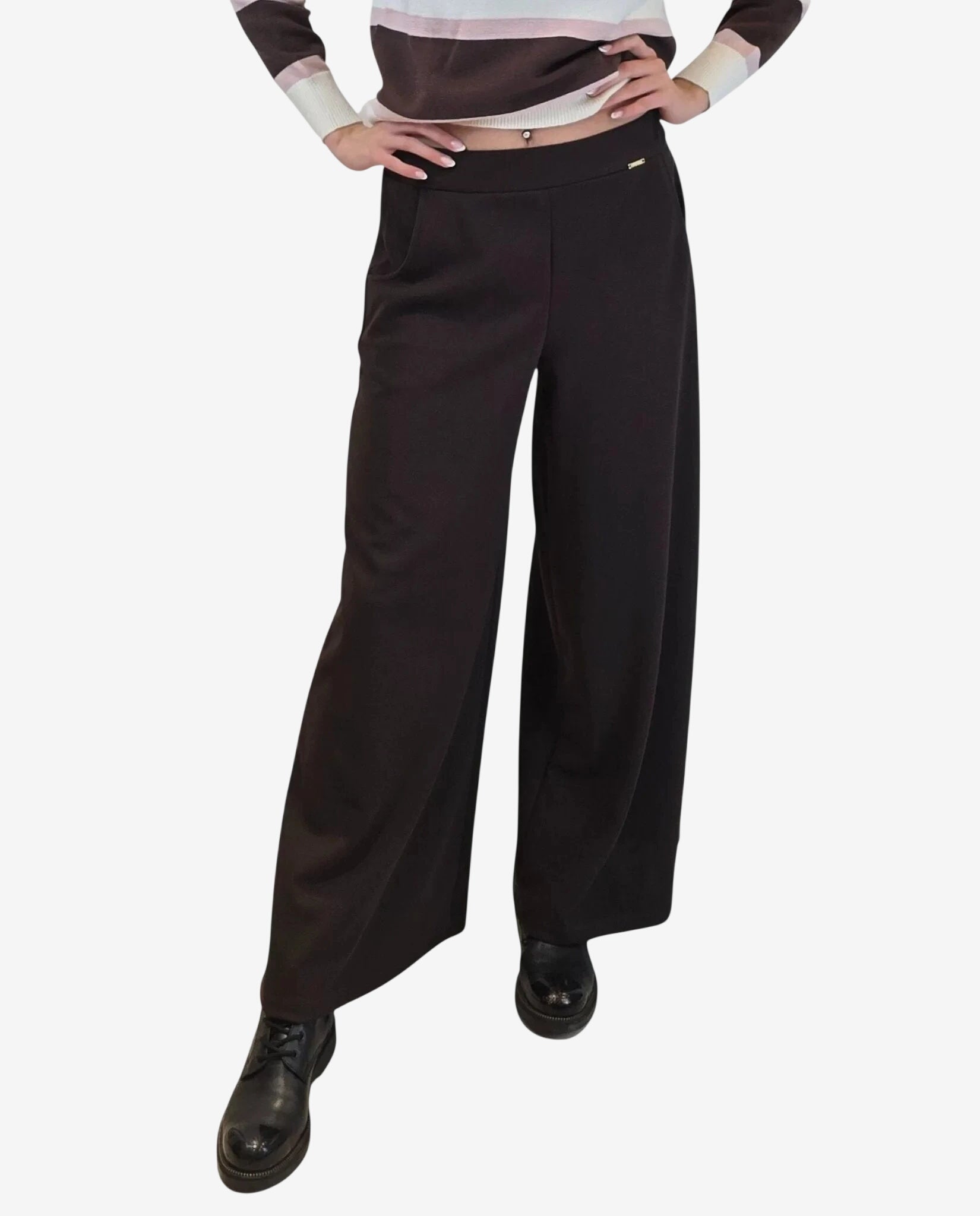 A person wears high-waisted, wide-leg moka brown trousers with a small gold-tone side detail.