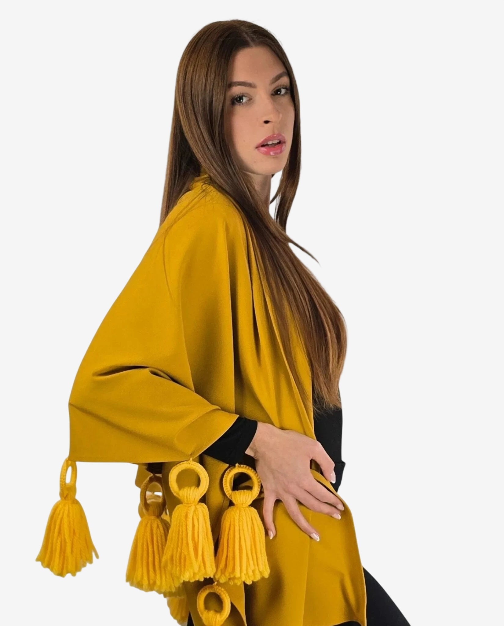 Mantella color ocra in viscosa punto milano decorata con nappe in lana merinos.