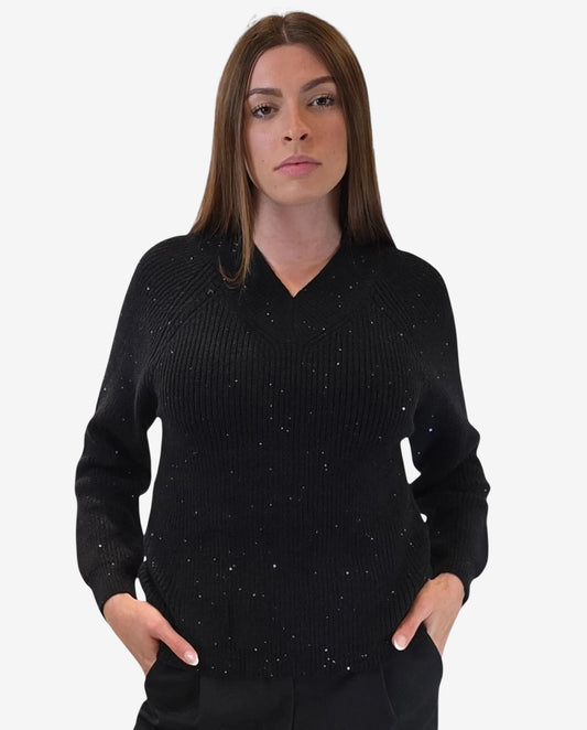 A woman wears a black V-neck pullover sweater featuring subtle light-reflecting metallic accents.