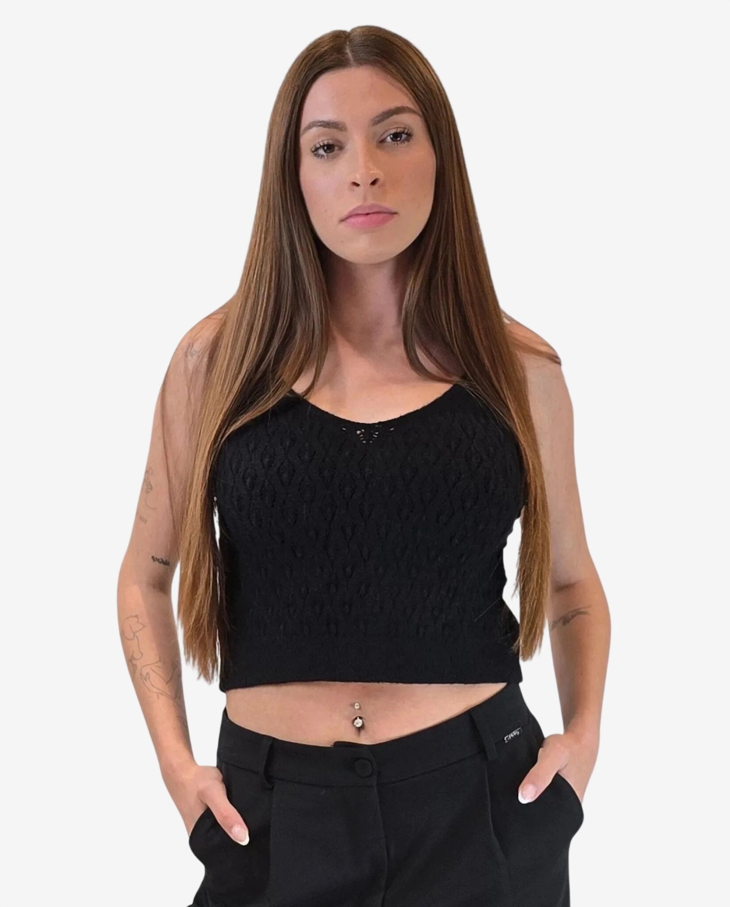 A woman wears a black sleeveless knit top with a textured pattern and a scoop neckline.