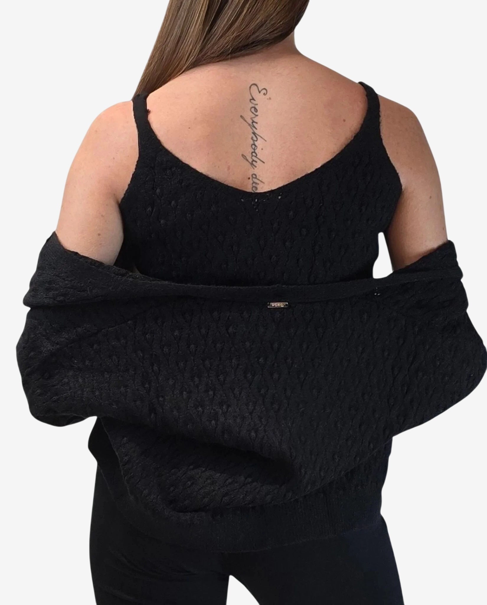 A woman wears a black textured tank top and a matching cardigan draped off her shoulders.