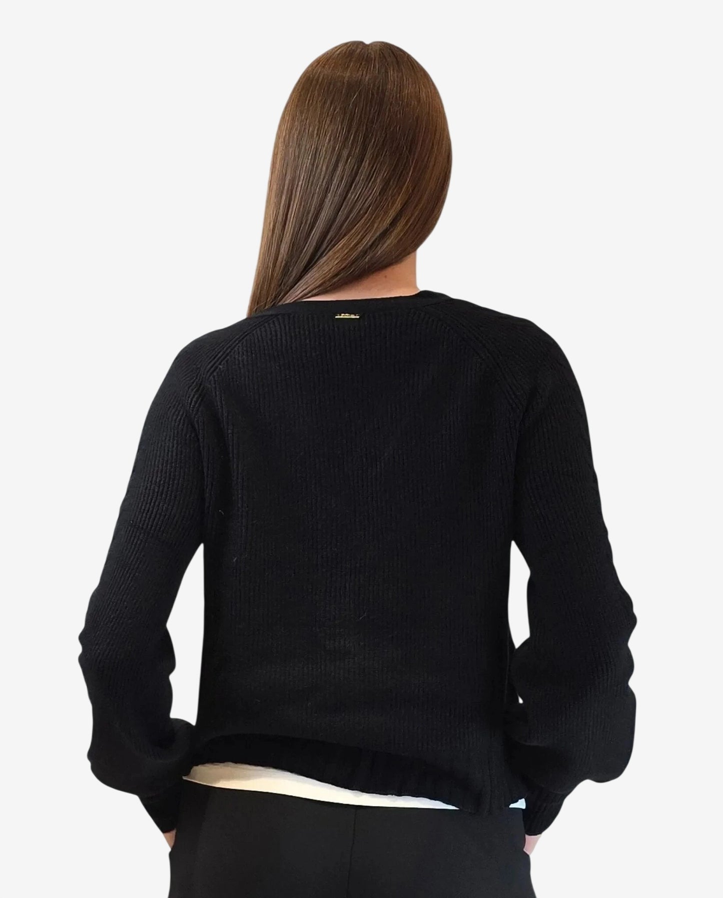 A person seen from behind wearing a black long-sleeved knit sweater with a small gold logo detail.