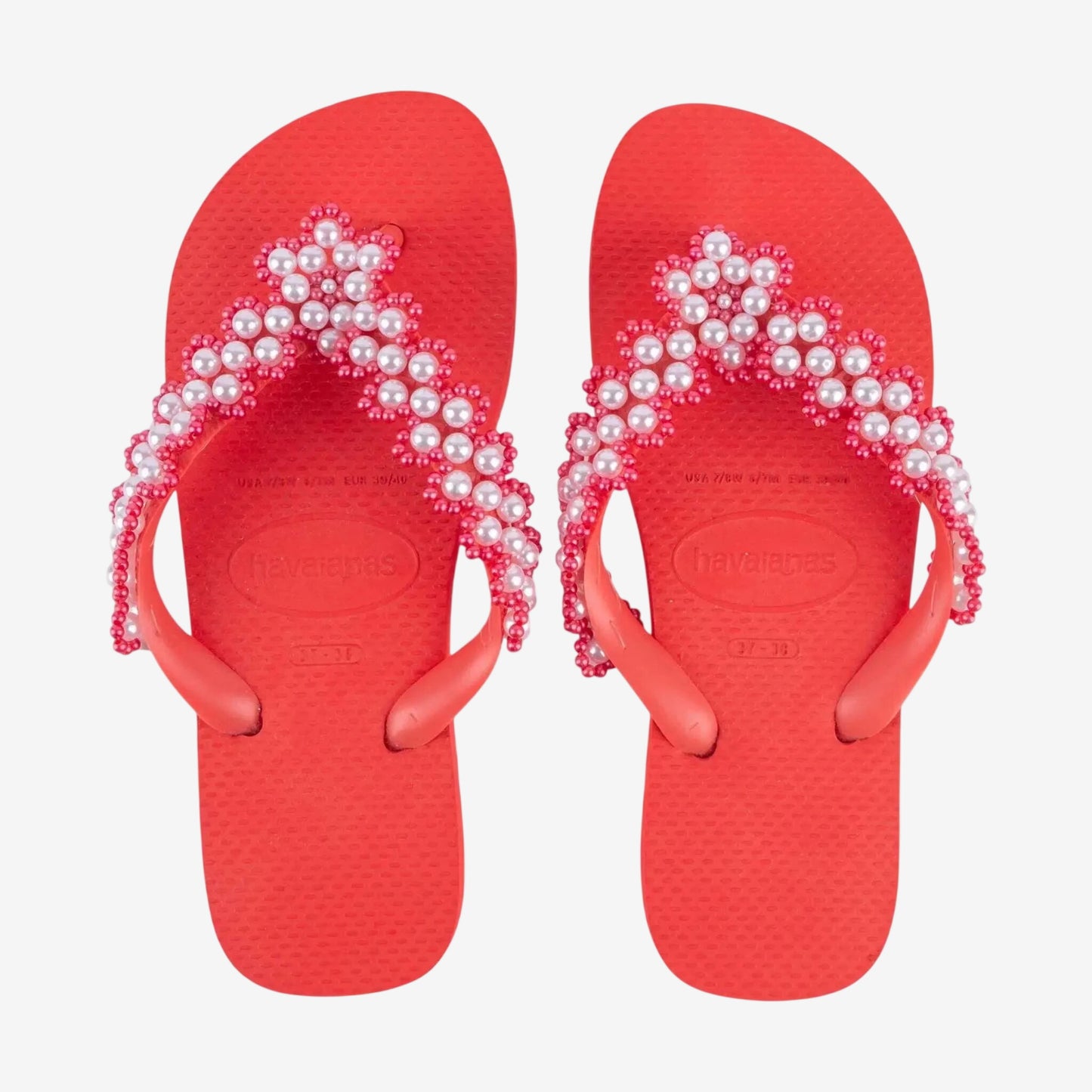 Infradito Havaianas rosse con cinturini decorati da un ricamo artigianale di perle bianche.