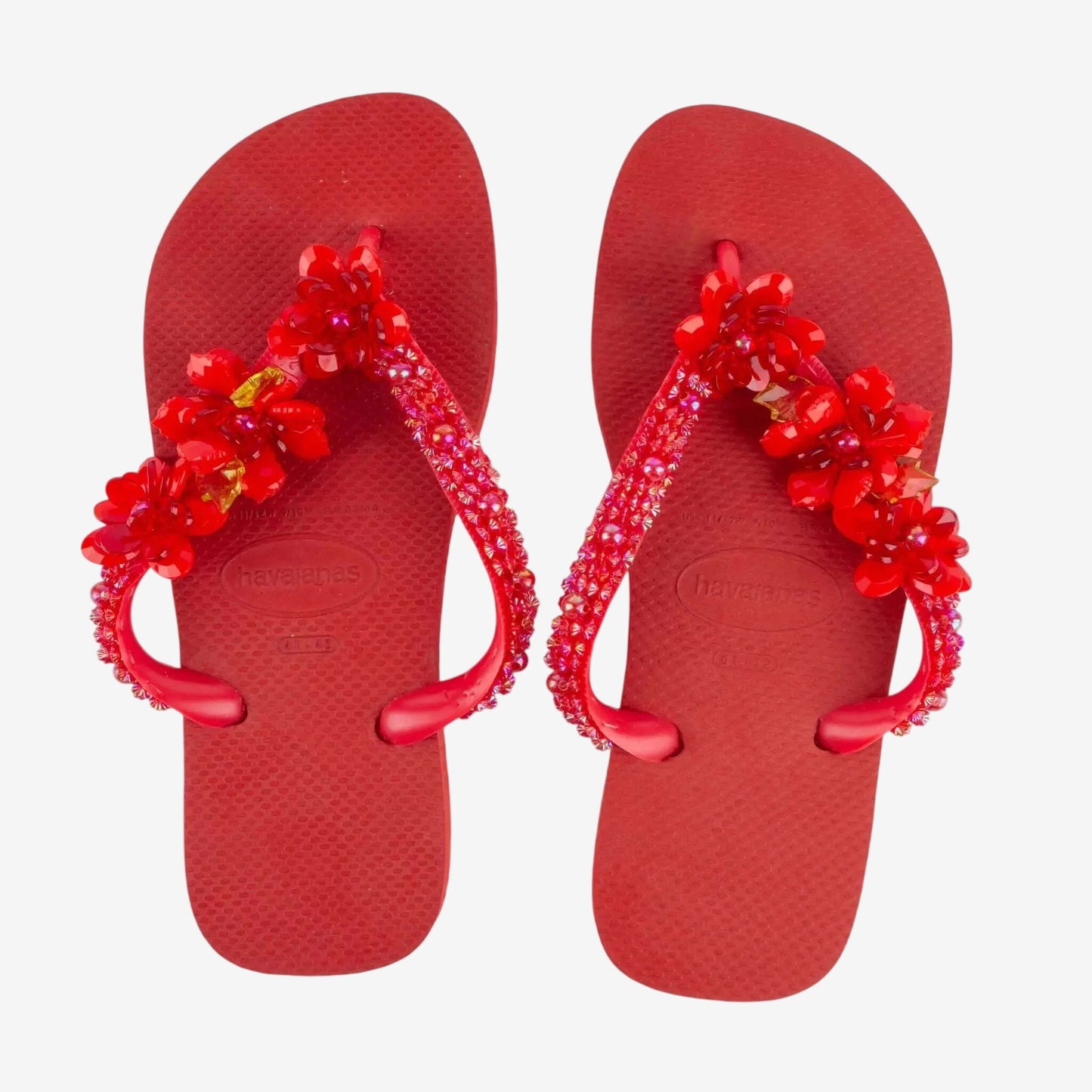 Infradito Havaianas rosse decorate con fiori e pietre preziose applicate a mano.