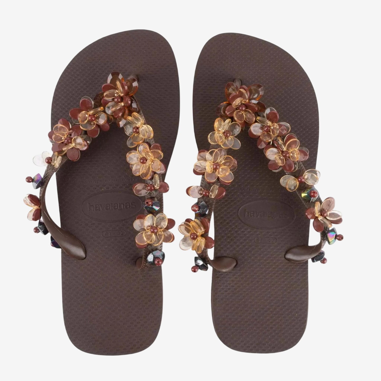 Infradito Havaianas marroni decorate con fiori e pietre preziose applicate sui cinturini.