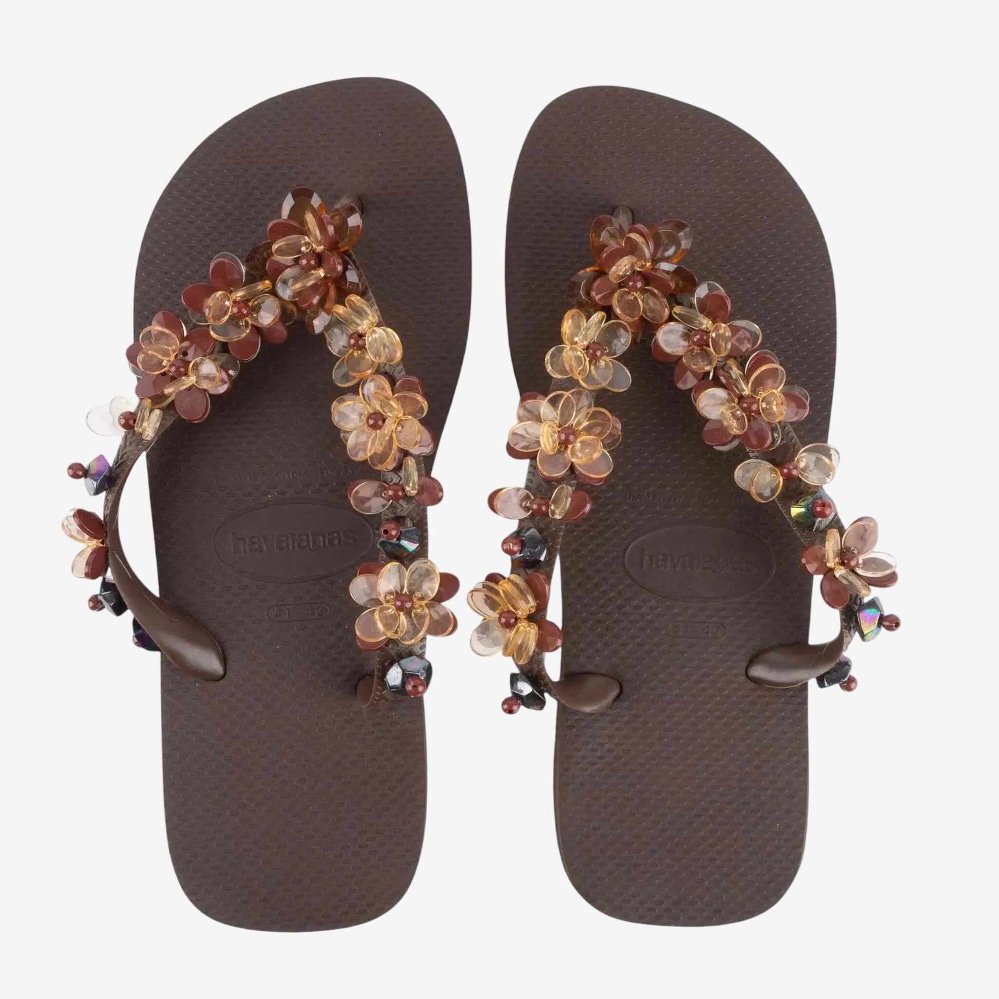 Infradito Havaianas marroni decorate con fiori e pietre preziose applicate sui cinturini.