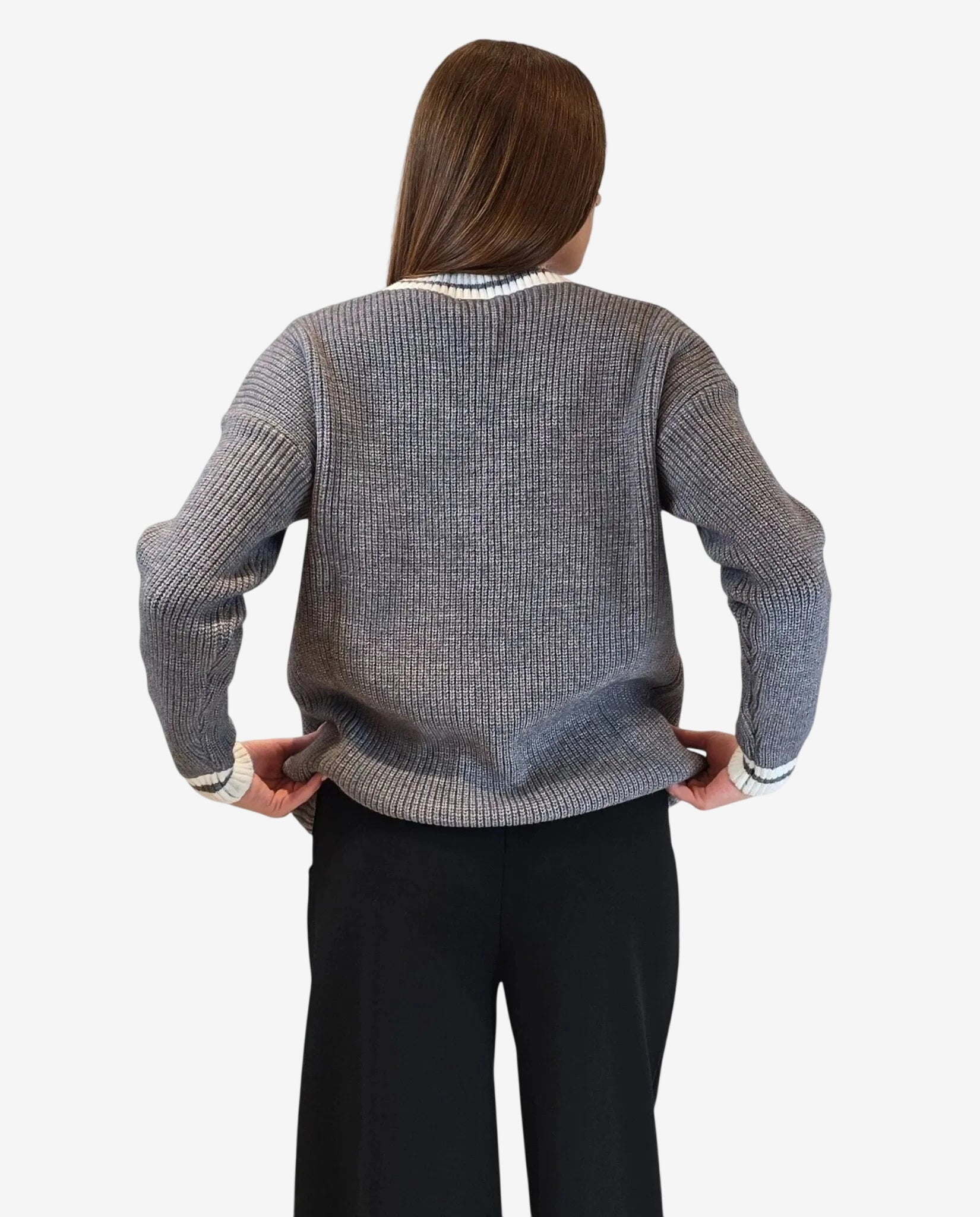 Una donna indossa un cardigan grigio a maglia grossa con bordi bianchi a contrasto.