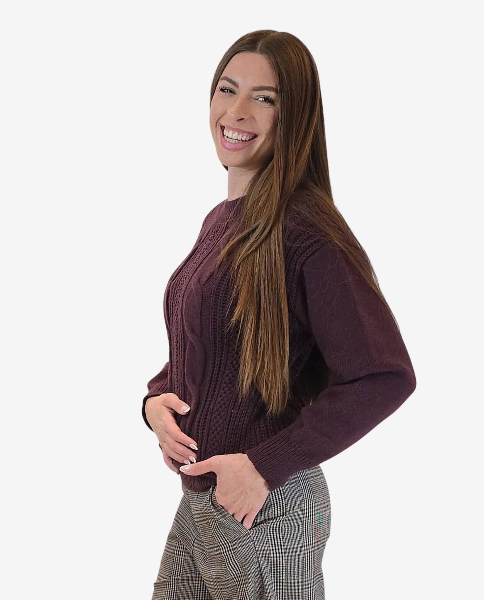 A woman wears a long-sleeved, burgundy cable-knit pullover sweater.