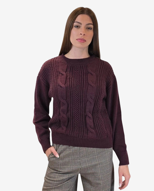 A woman wears a long-sleeved, burgundy cable-knit pullover sweater with a crew neckline.