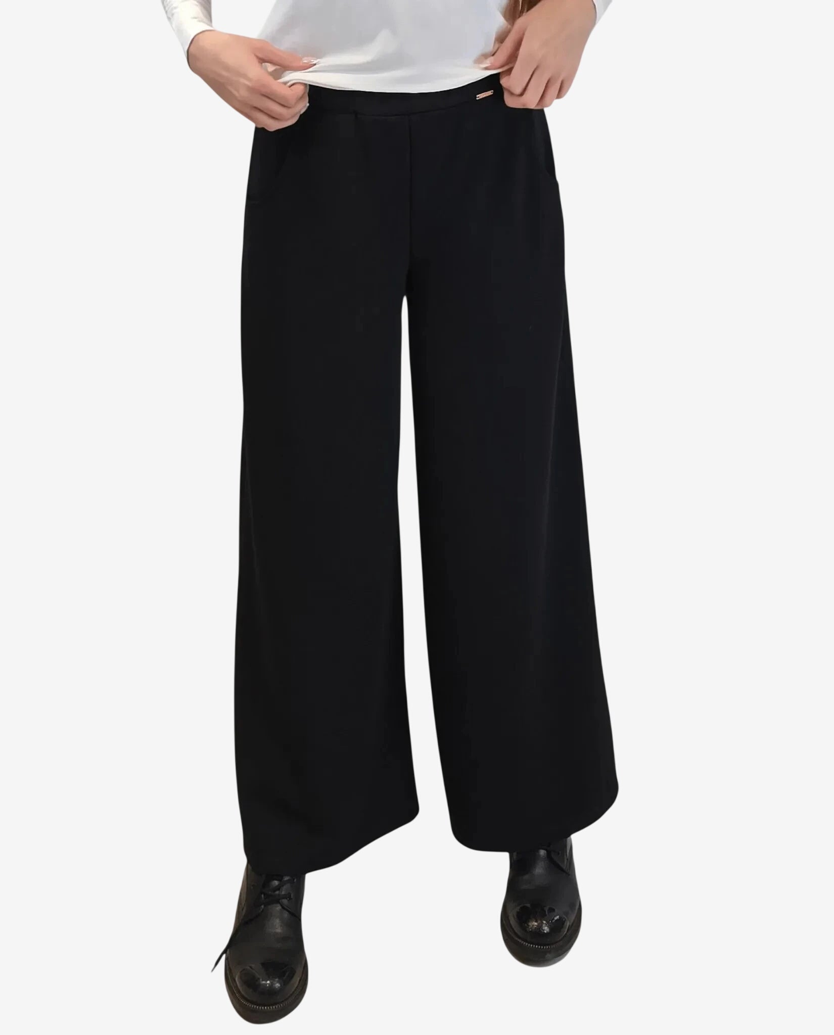 A person wears black wide-leg trousers with a high waist and a small metallic detail.