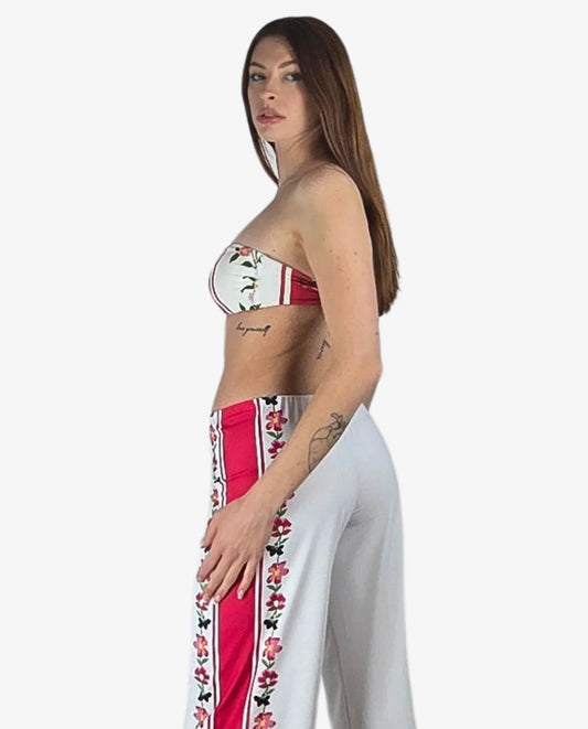 Pantalone palazzo bianco in lycra con bande laterali rosse a motivi floreali.