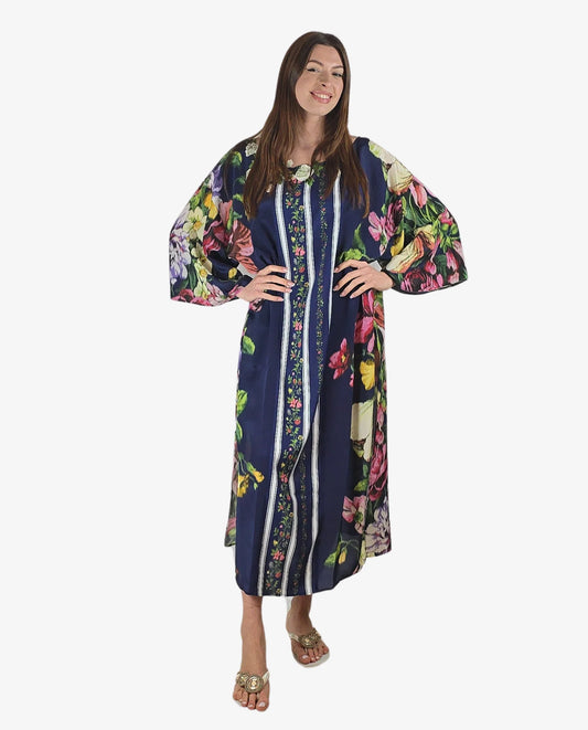Modella indossa un poncho lungo in viscosa blu con fantasia floreale multicolor e maniche kimono.