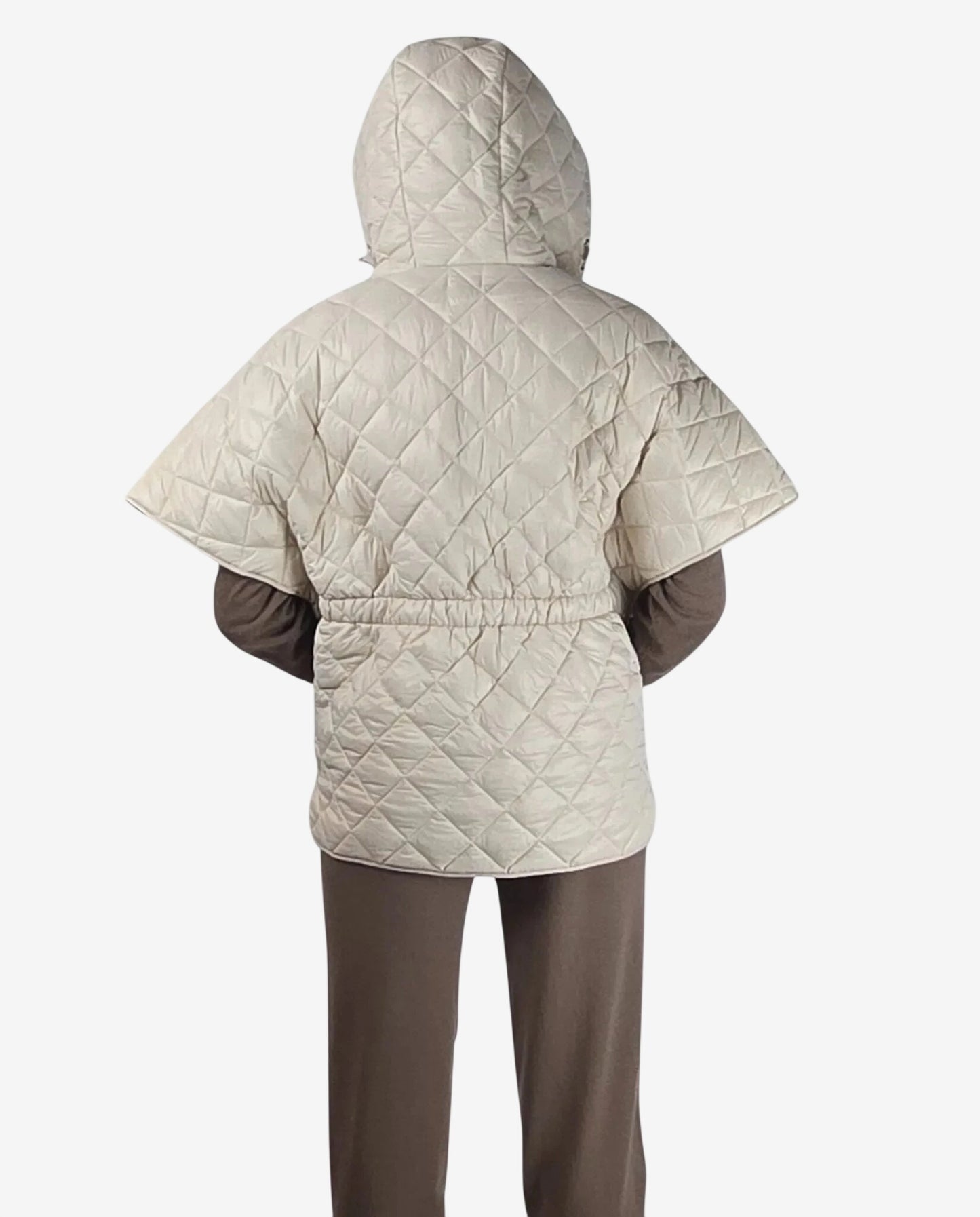 A beige quilted hooded cape with short sleeves and a cinched waist worn over brown clothing.