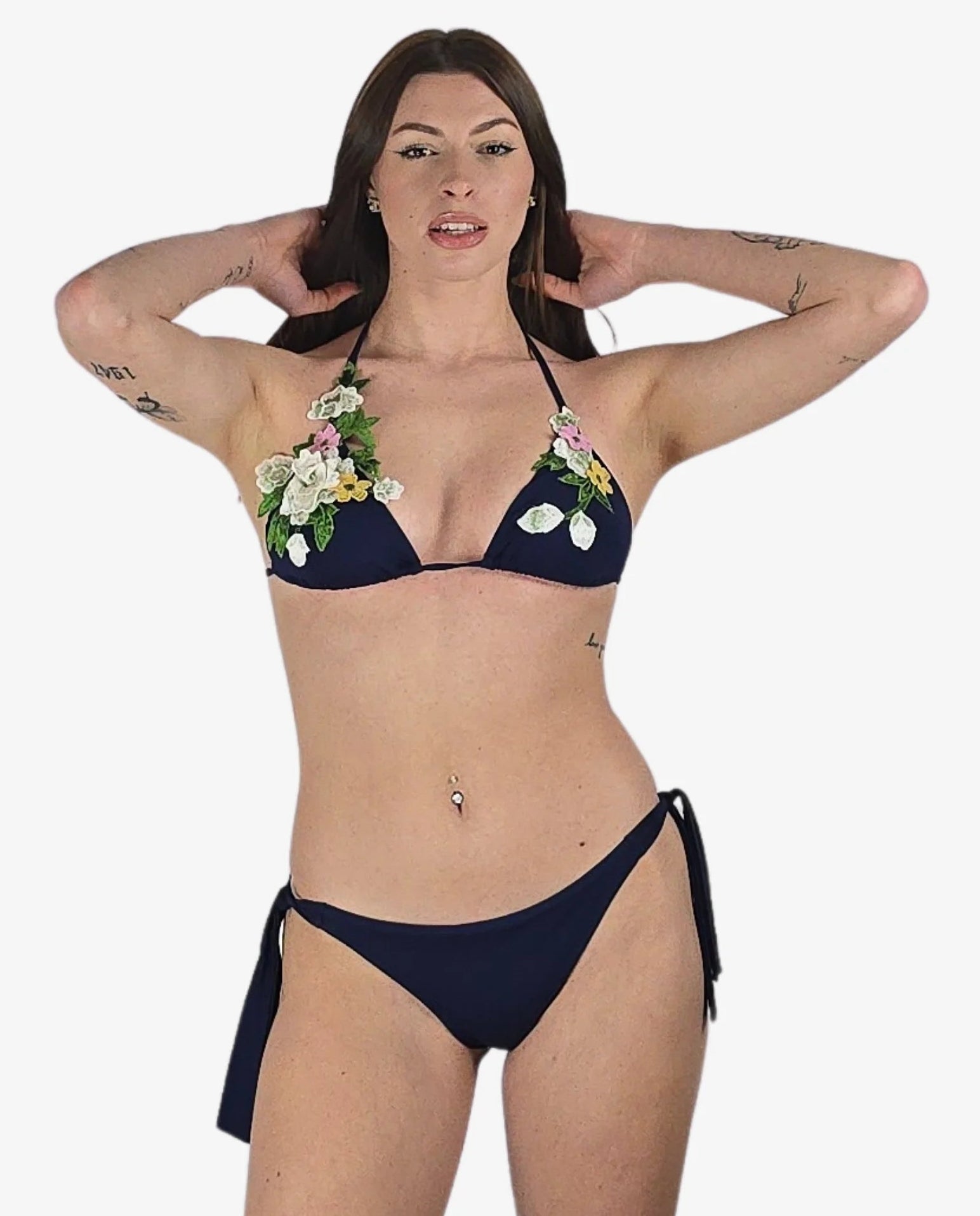 Bikini a triangolo blu scuro con fiori 3D applicati e slip con laccetti laterali.