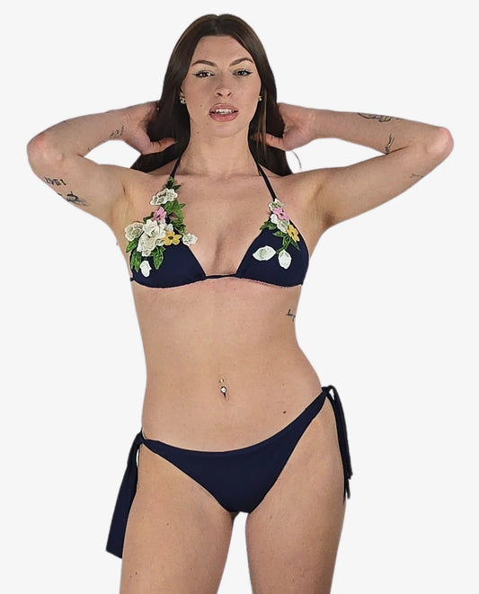 Bikini a triangolo blu scuro con fiori 3D applicati e slip con laccetti laterali.