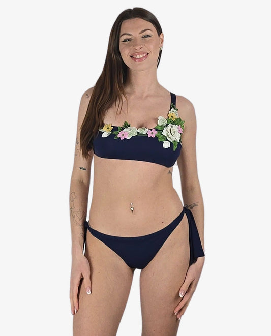 Bikini monospalla blu scuro con applicazioni floreali 3D e slip con laccetti laterali.