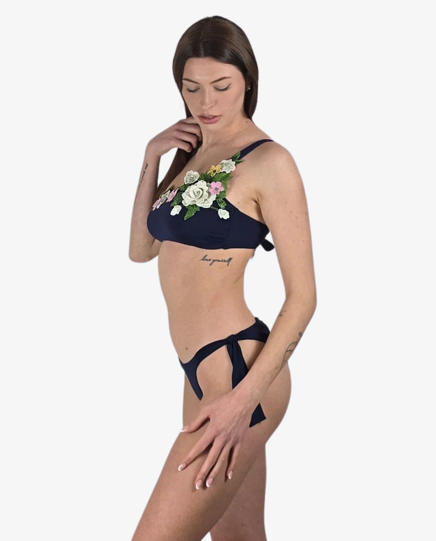 Bikini monospalla blu scuro con applicazioni floreali 3D e slip con laccetti laterali.