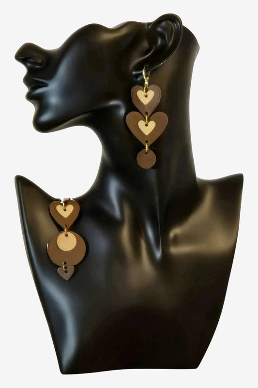 Orecchini pendenti in pelle marrone a forma di cuori e cerchi su un manichino nero.