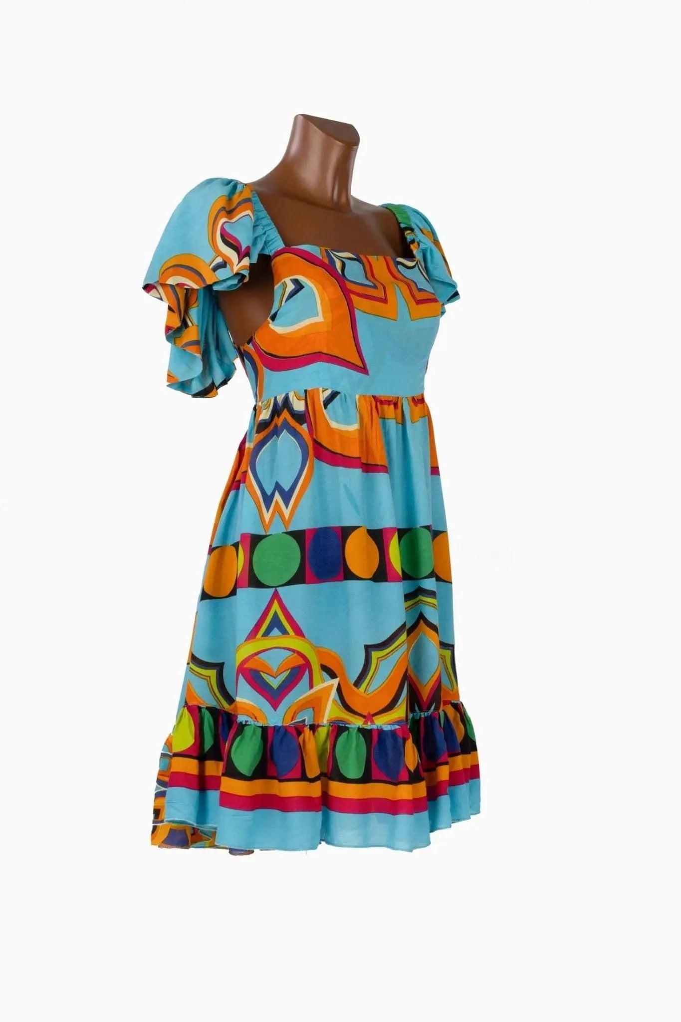 Abito corto azzurro con stampa geometrica colorata, scollo sulla schiena e volant sulle spalle.