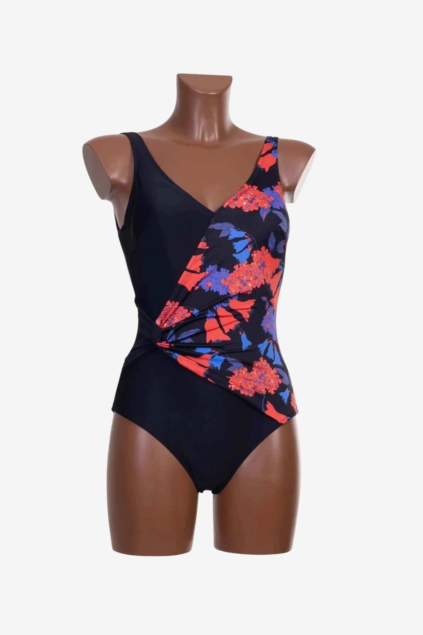 A black one-piece swimsuit with a floral patterned wrap-style front detail on a mannequin.