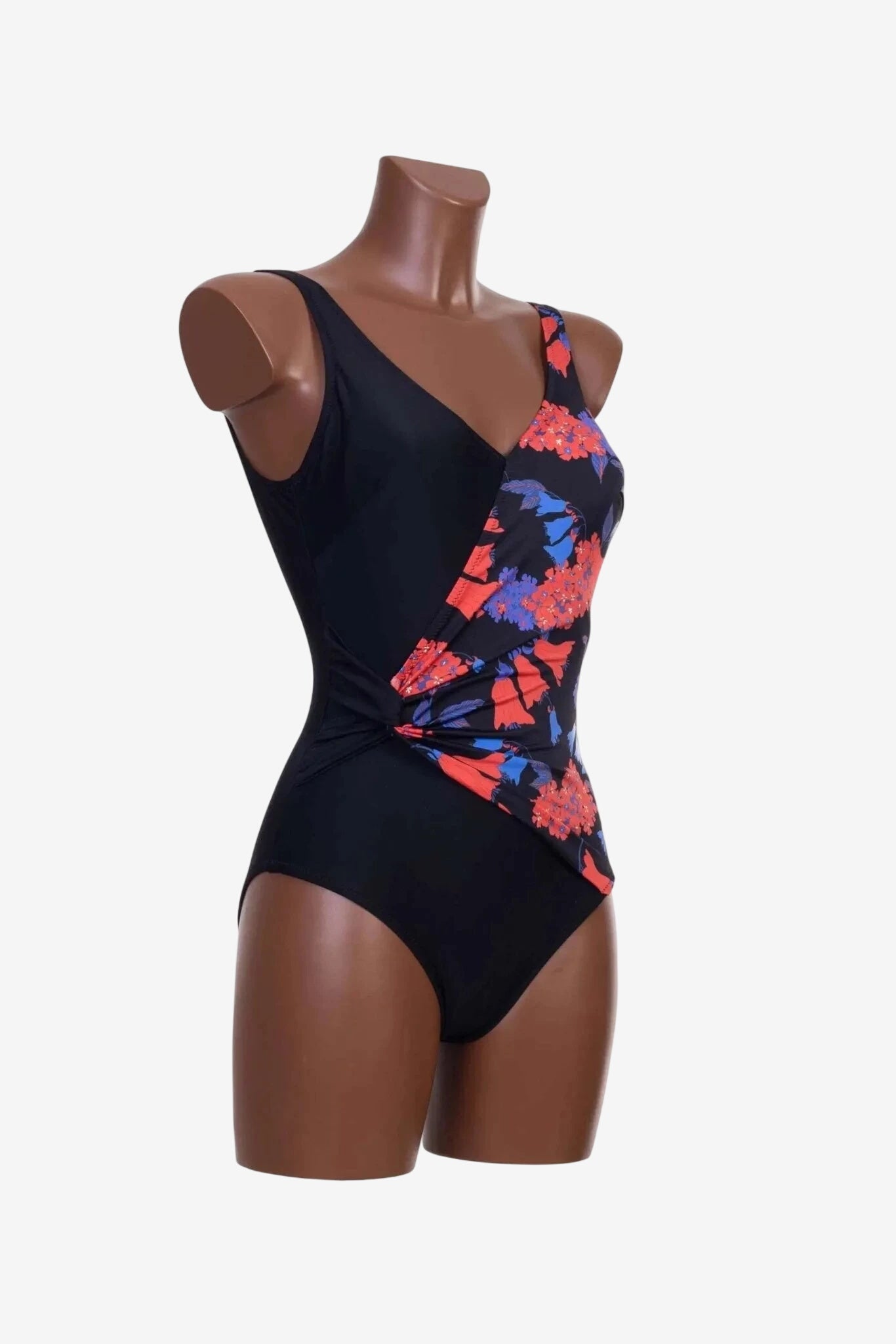 A black one-piece swimsuit with a floral patterned wrap-style front detail on a mannequin.