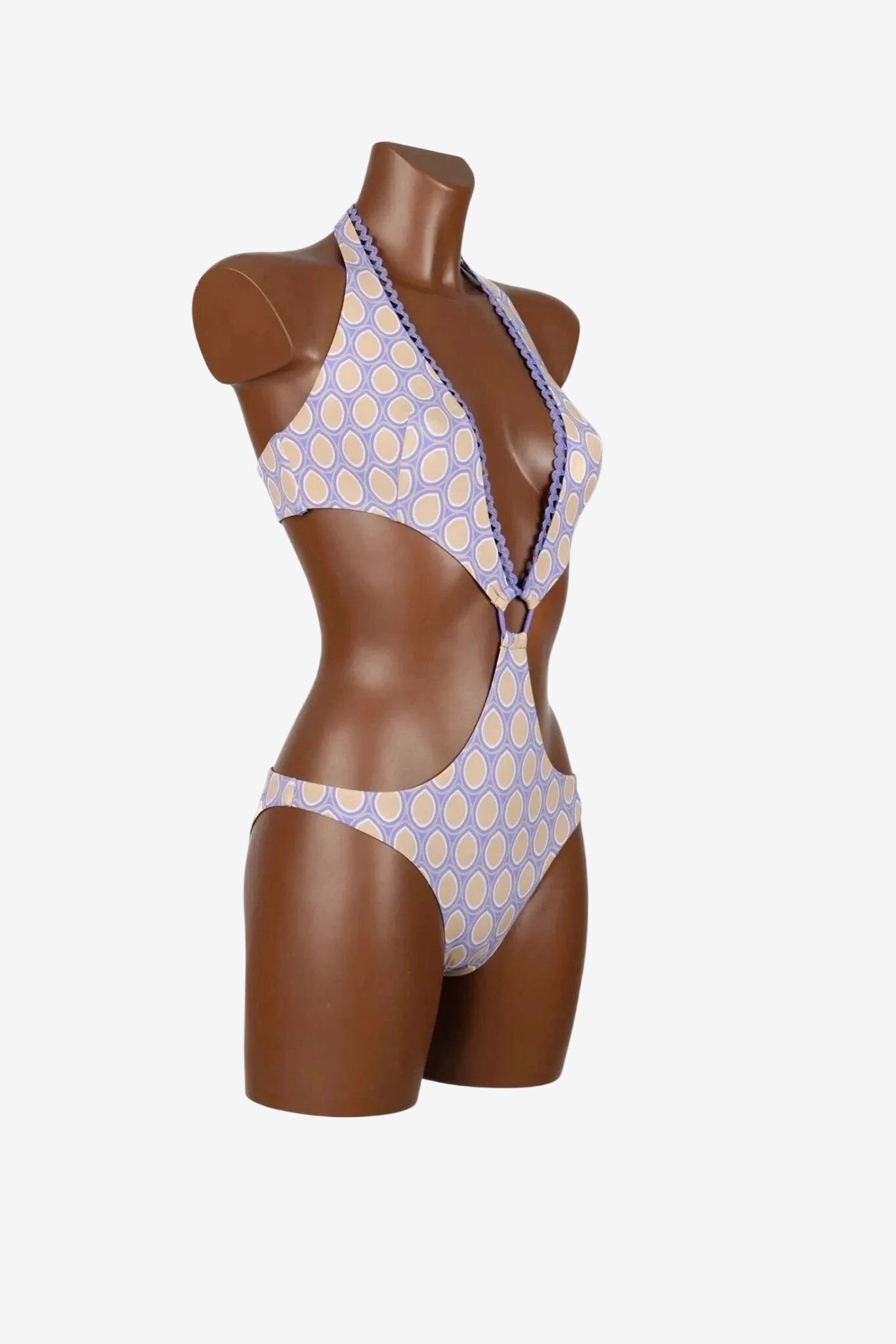 Trikini intero con stampa geometrica color lilla e beige e bordi smerlati su manichino.
