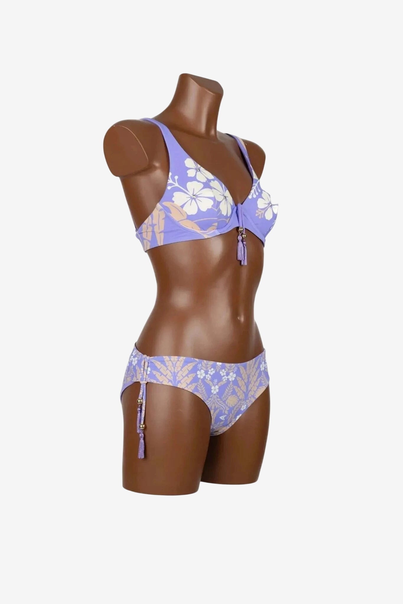 Bikini con ferretto color lilla a stampa floreale con dettagli a nappa su un manichino.