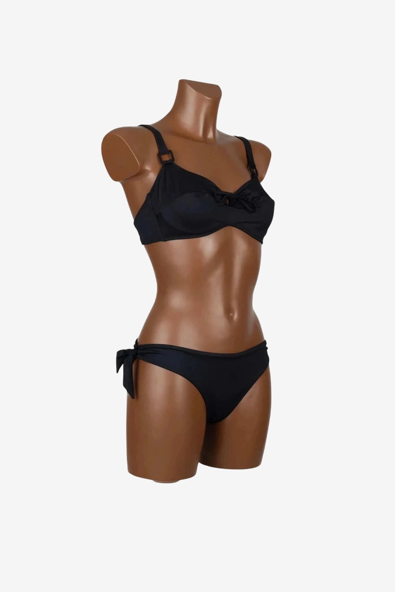 Bikini nero con ferretto, coppe non imbottite e slip con fiocchi laterali su manichino.
